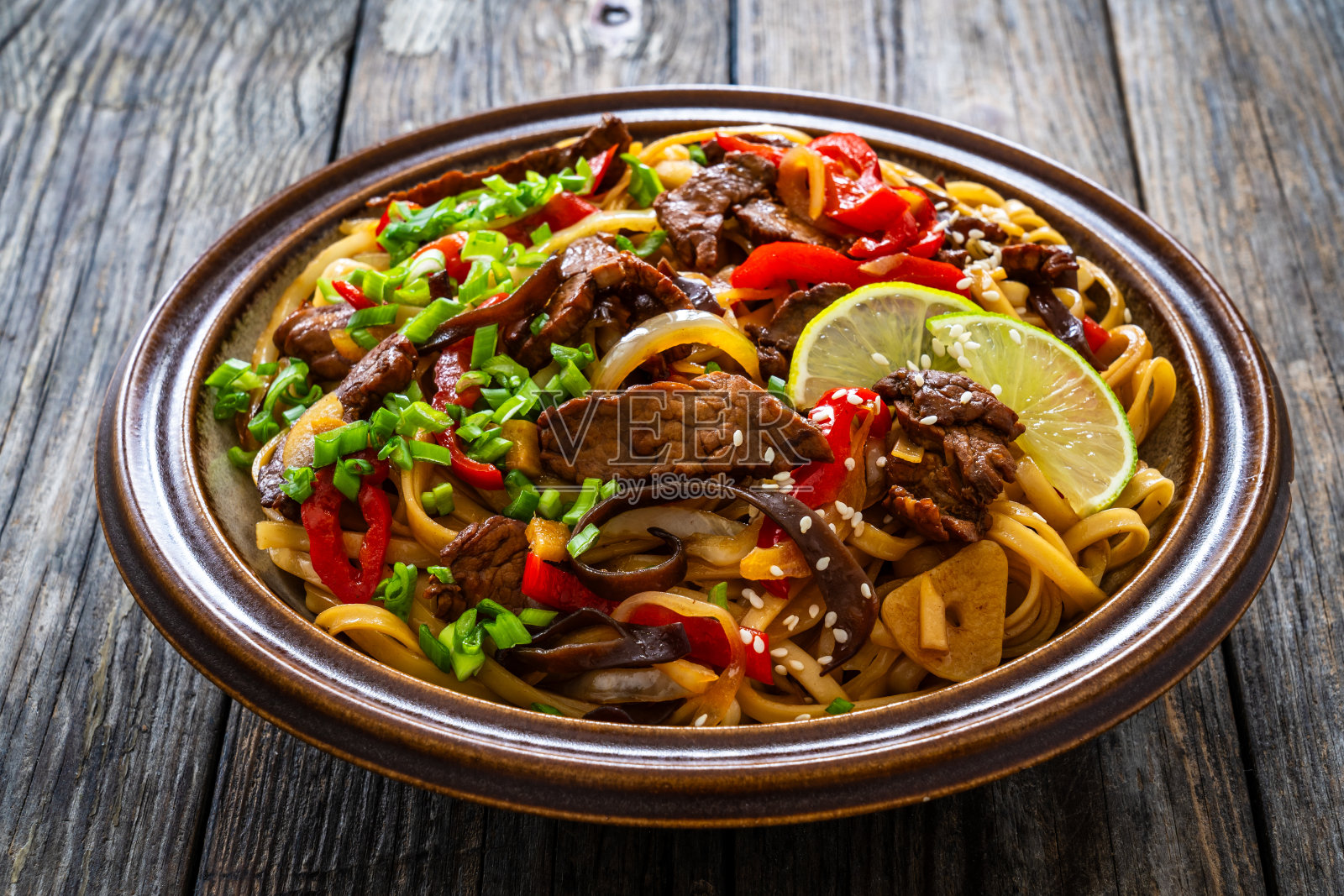 木桌上的亚洲风味炒菜、烤牛肉和炒面照片摄影图片