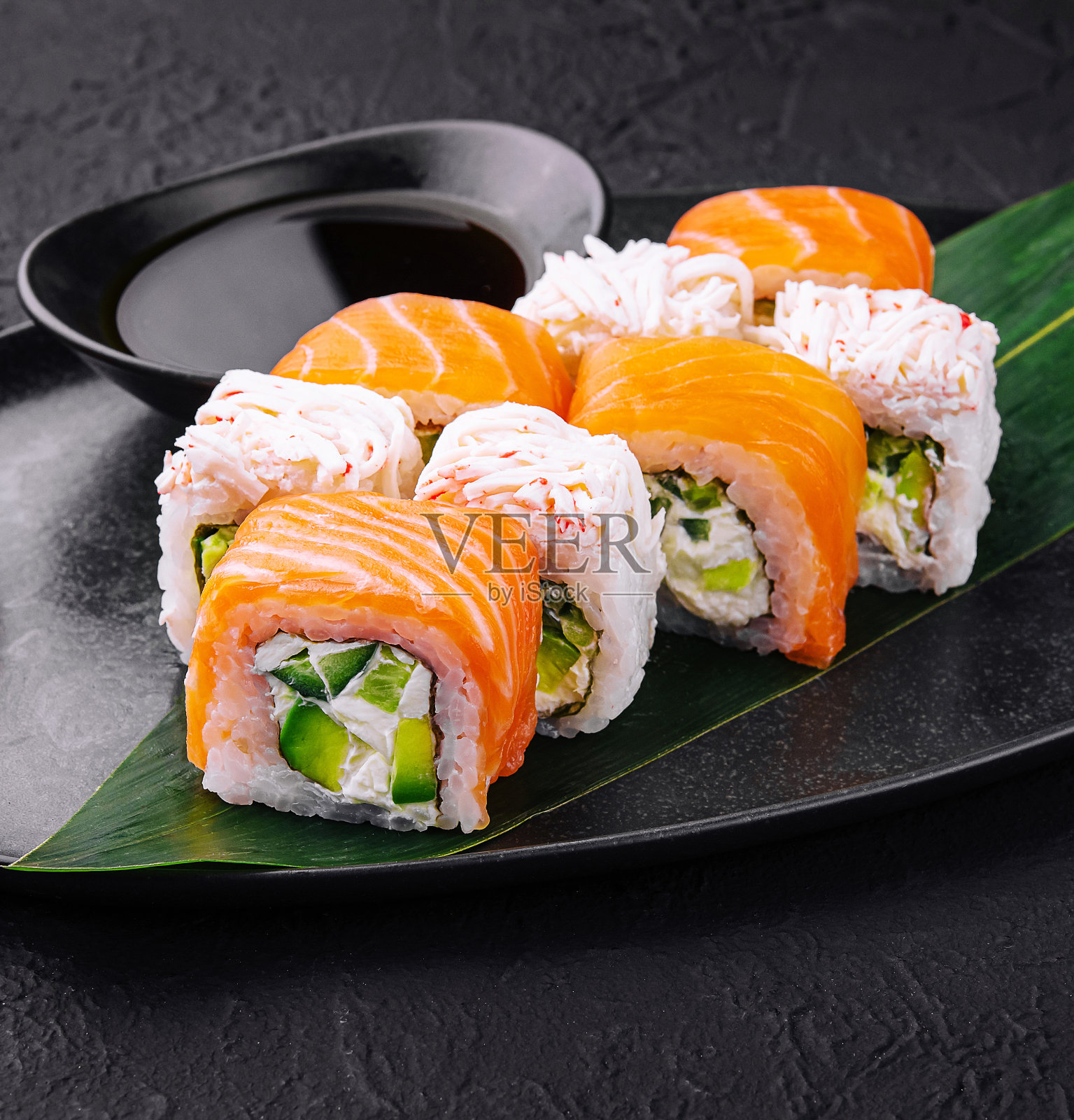 寿司卷，鲑鱼和螃蟹在黑色盘子照片摄影图片