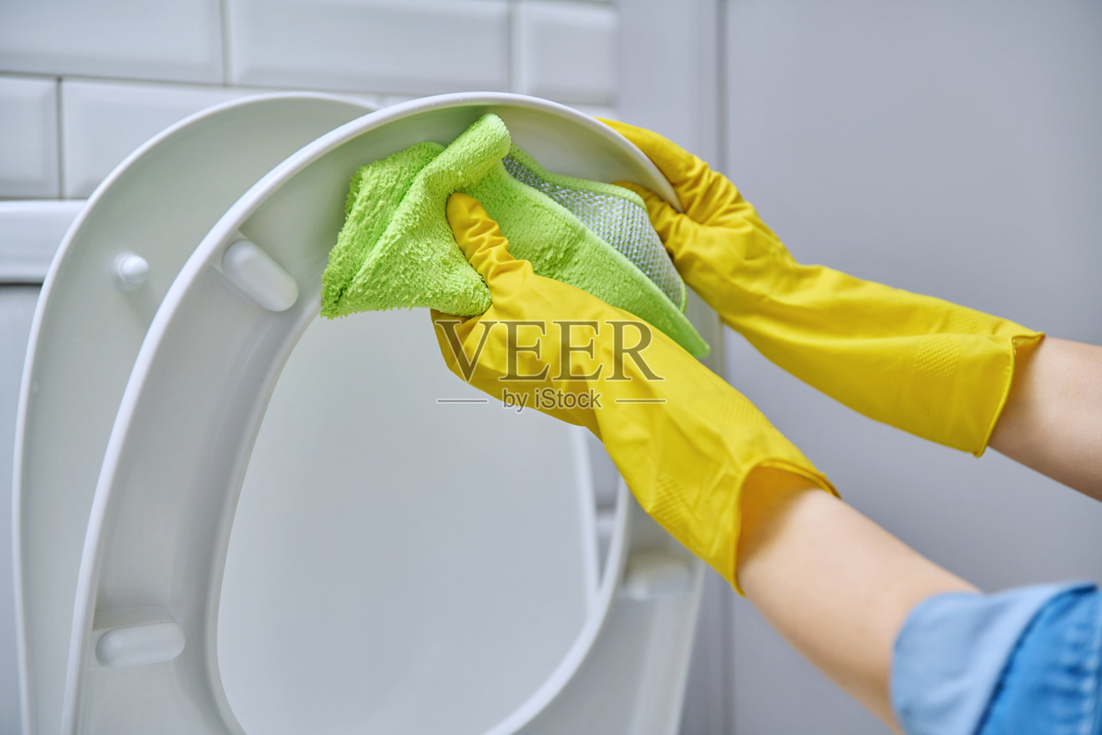 戴着防护手套的手在浴室里清洁马桶照片摄影图片