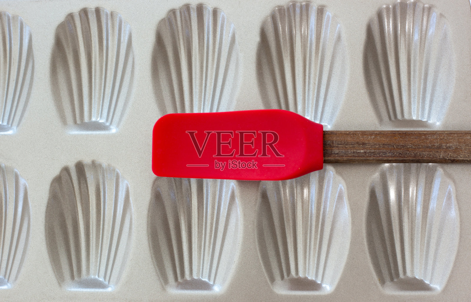 玛德琳蛋糕平底锅特写全画幅，红色抹刀照片摄影图片