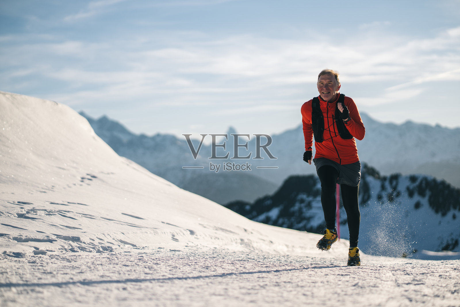 冬季，资深男越野跑运动员沿着雪山小径跳跃照片摄影图片