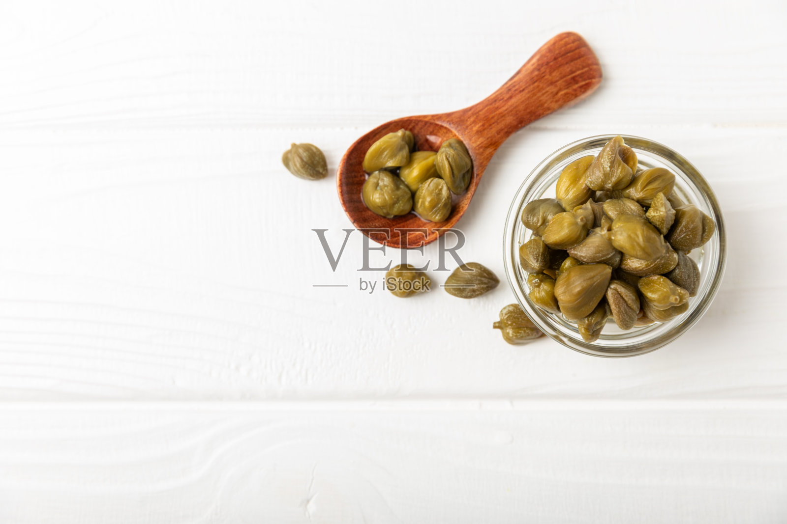 木桌上的玻璃罐子里装着刺山柑。刺山柑加海盐和迷迭香。腌酸豆。地中海菜的食材。有机香料和调味料。副本的空间。照片摄影图片