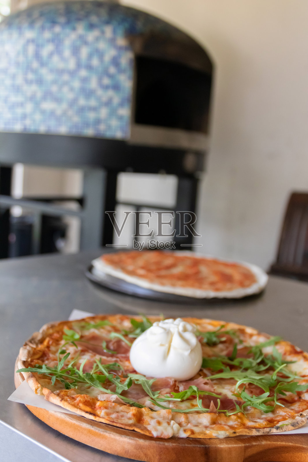 意大利披萨上的布拉塔奶酪，配以意大利熏火腿和芝麻菜，放在木板上，背景是传统的烤箱。照片摄影图片