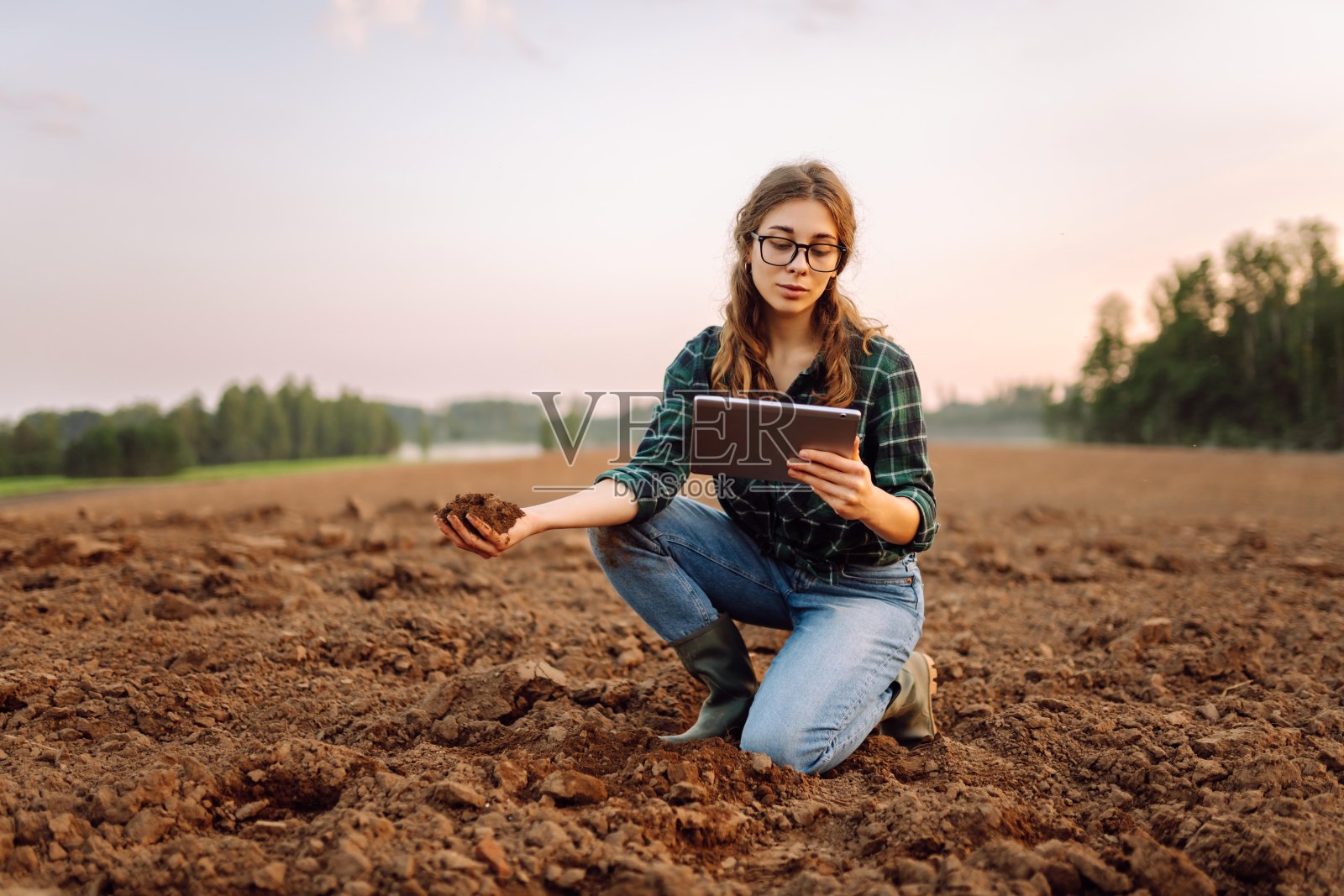 一名妇女在种植蔬菜种子或植物幼苗前检查土壤的健康状况。照片摄影图片