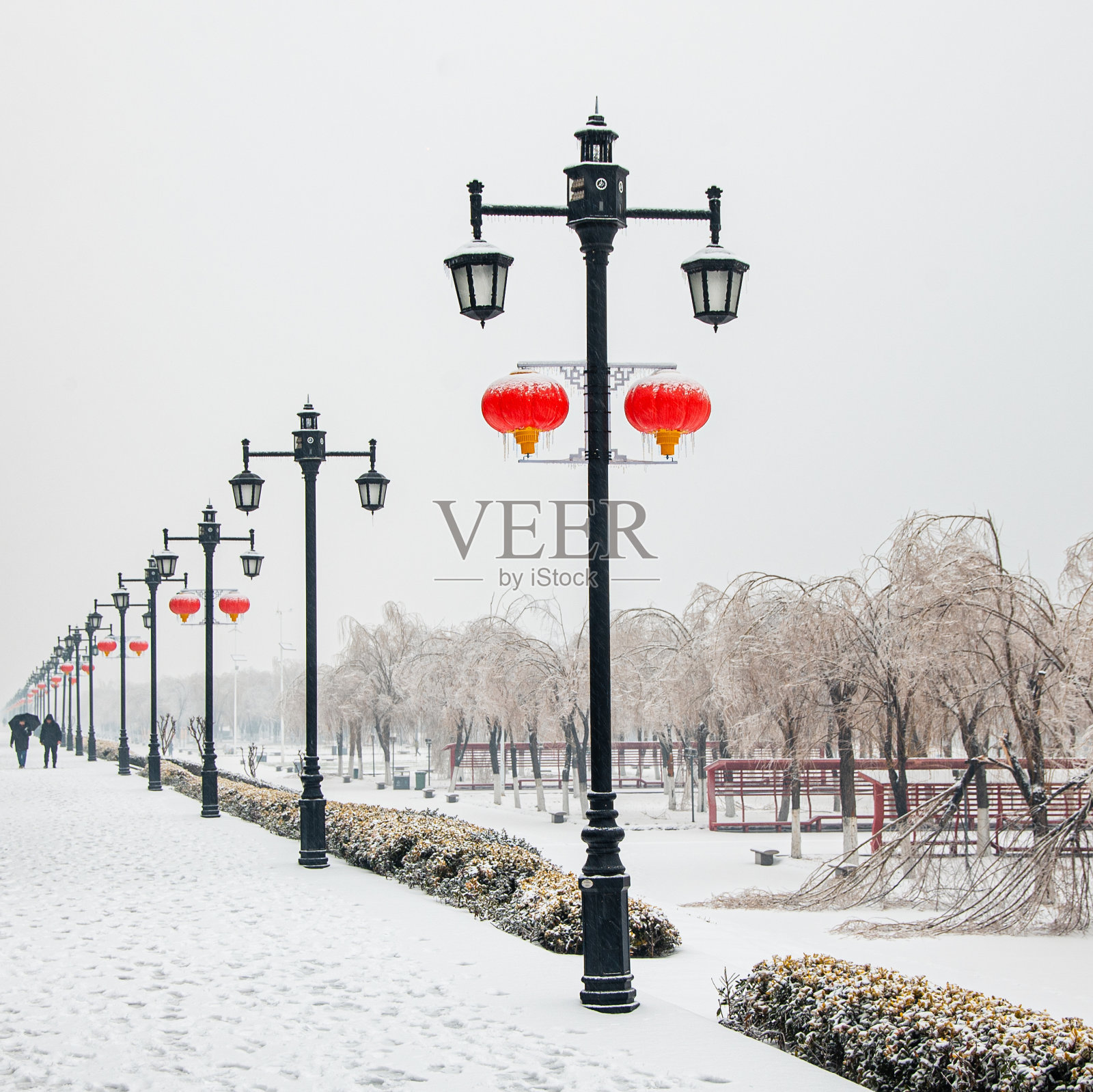 在中国武汉一个冰雪覆盖的公园里，路灯上挂着红灯笼照片摄影图片
