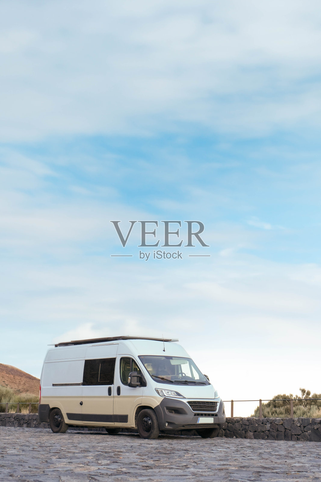 白色面包车停在鹅卵石路上，周围是自然景观照片摄影图片