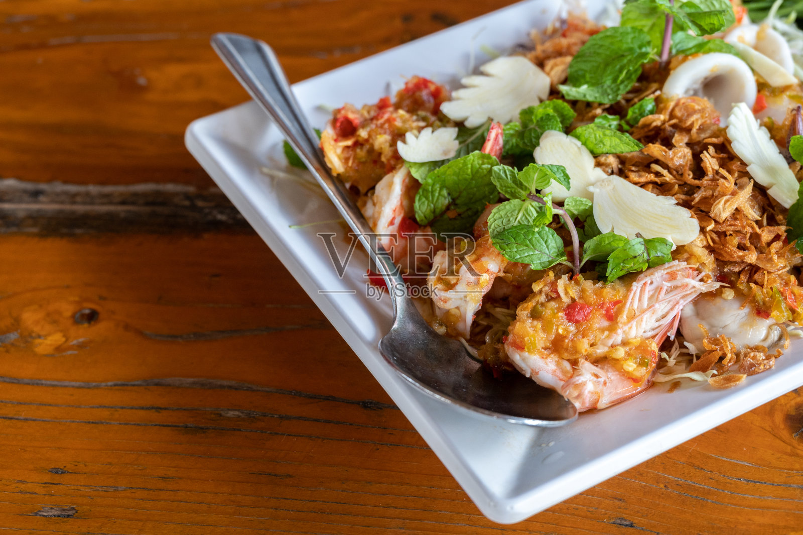 木桌上的泰式辣虾沙拉特写。照片摄影图片