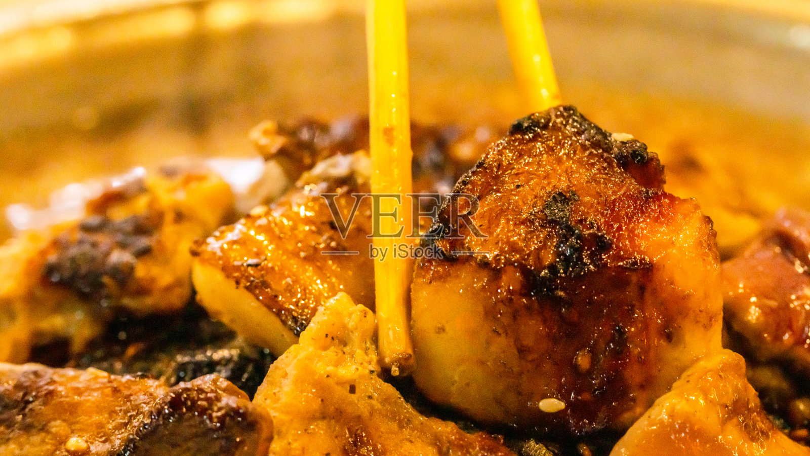 平底锅里的烤猪肉已经烧焦变黑了。它是一种致癌物质。它对健康有害。正在被朋友吃的筷子照片摄影图片