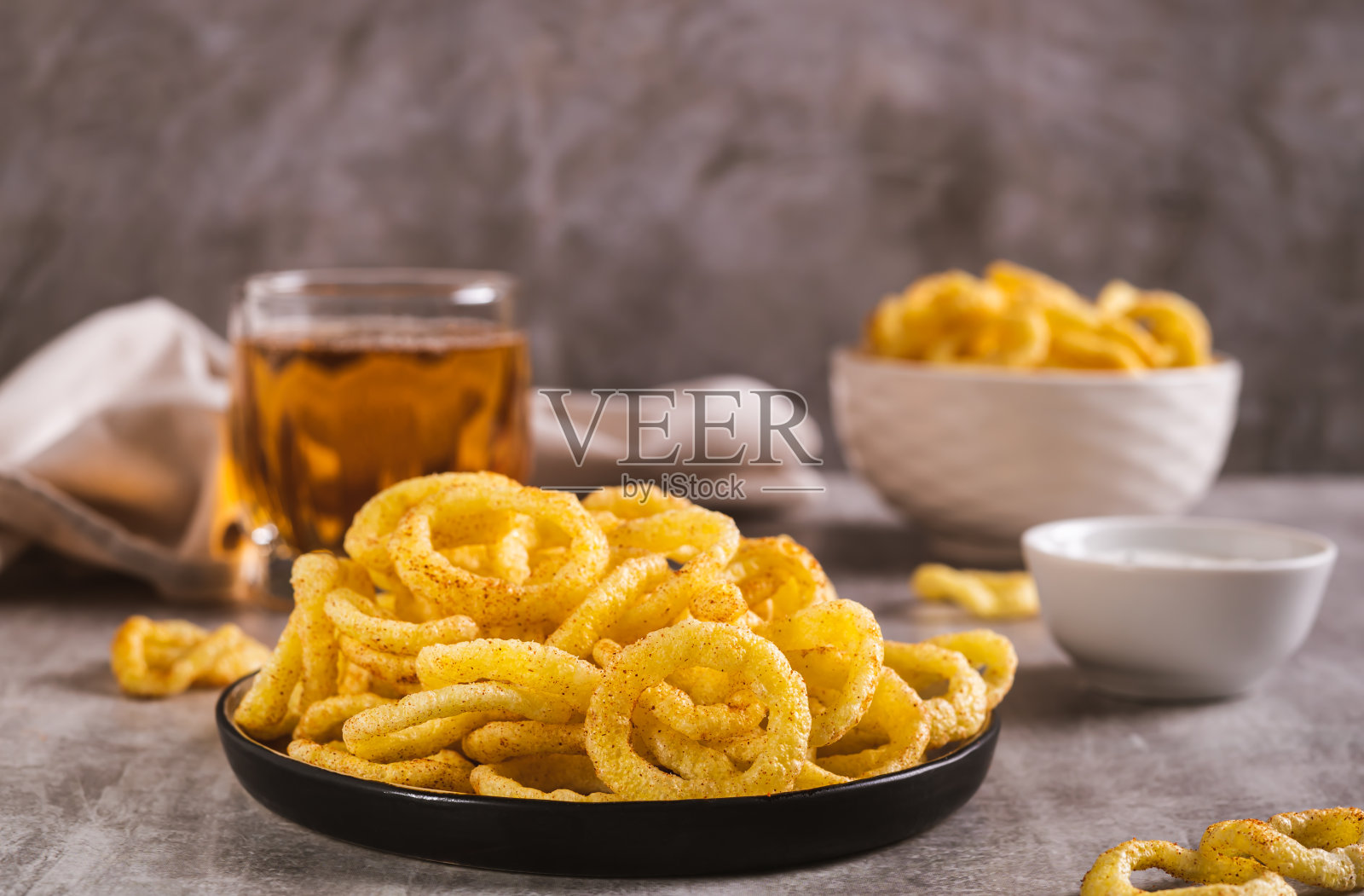洋葱圈，酱汁和啤酒放在桌子上的杯子里照片摄影图片