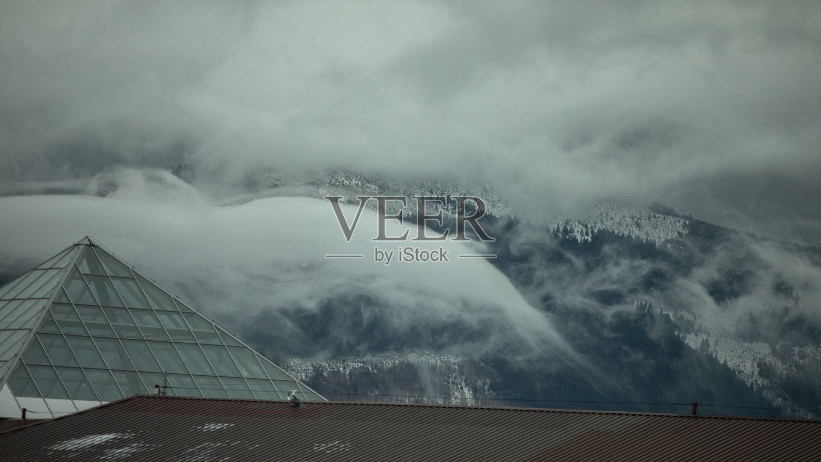 雾蒙蒙的冬季景观，背景是白雪覆盖的山脉和云彩照片摄影图片