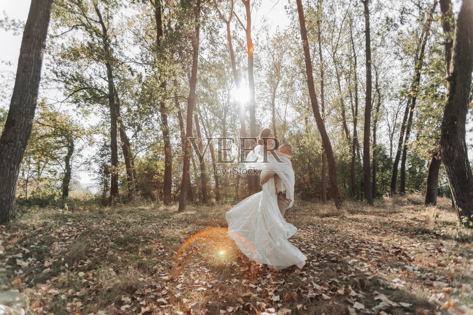 在一个美丽的秋日里，新郎把新娘抱在怀里照片摄影图片