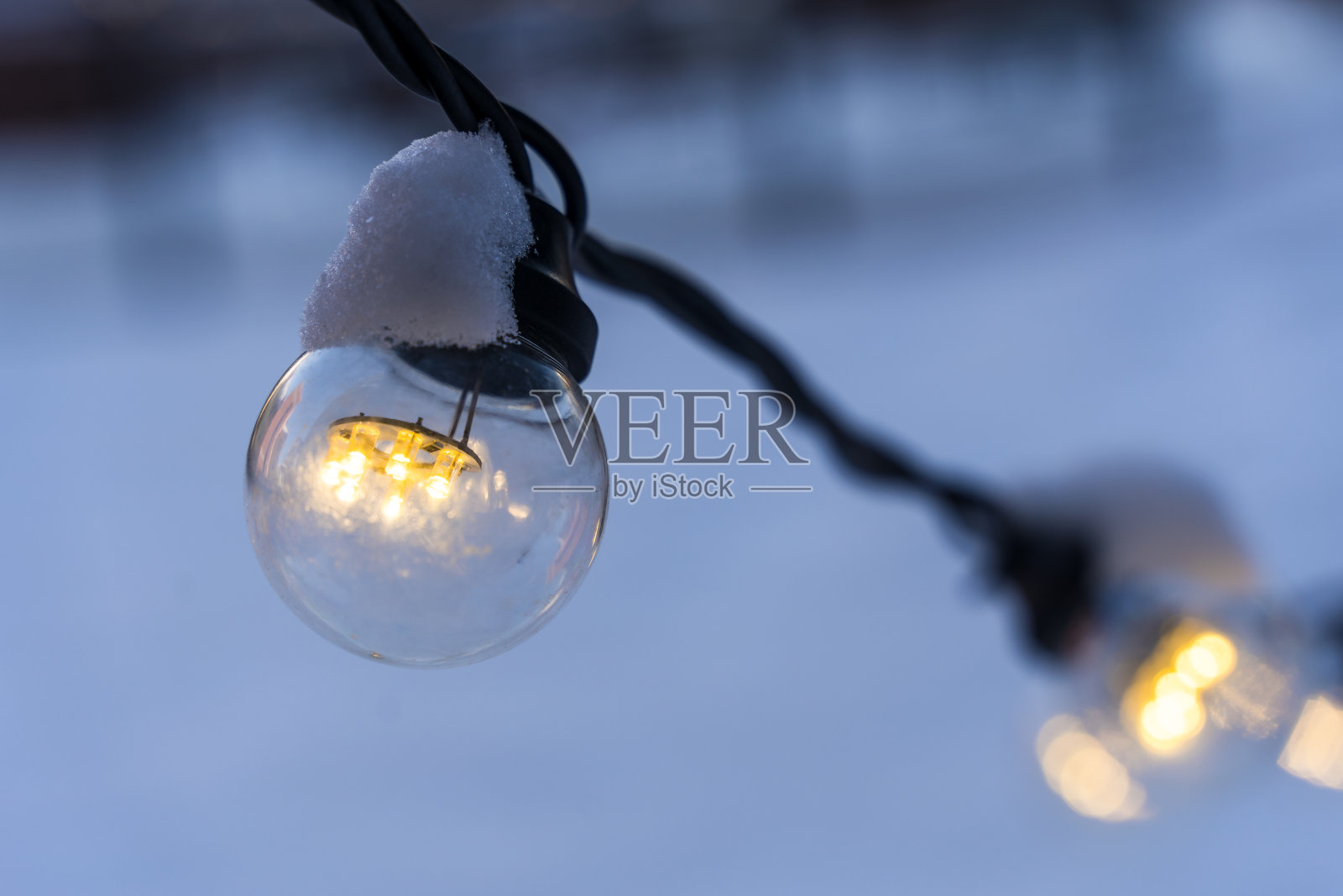 冬雪傍晚的球茎花环。由灯泡制成的户外电器装饰照片摄影图片