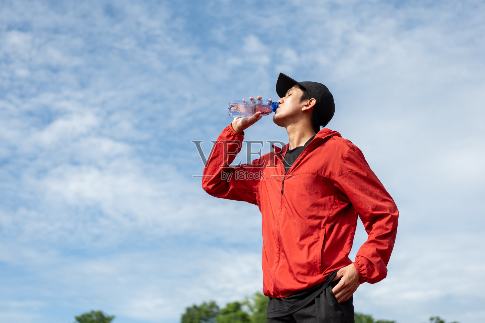 英俊的印度男子在体育馆内锻炼后喝水。年轻的亚洲男子在室外跑道慢跑后喝水。健康积极的生活方式理念。照片摄影图片