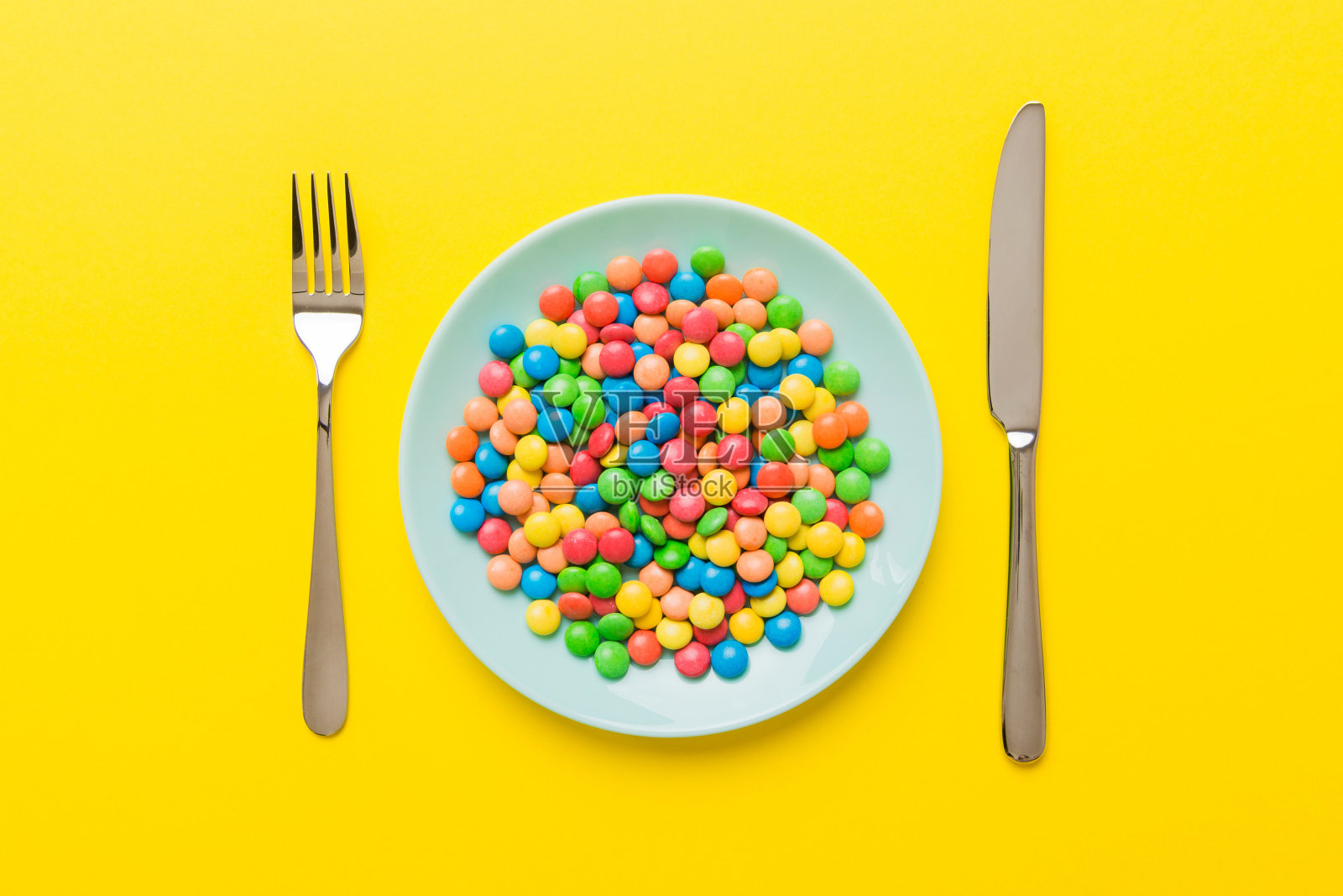 桌上的餐具和一盘甜糖。健康与肥胖概念，彩色背景俯视图照片摄影图片