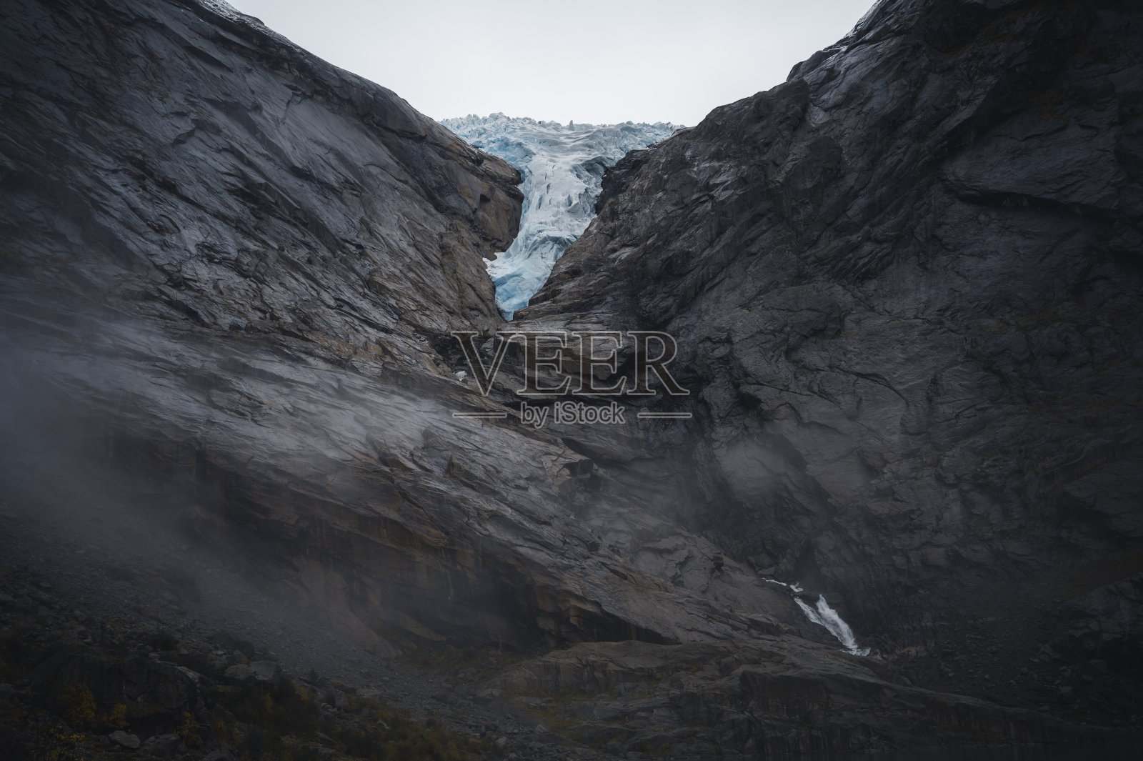 布里克斯达尔冰川之舌，挪威(布里克斯达尔斯林)，在岩石上，有雾和云。照片摄影图片