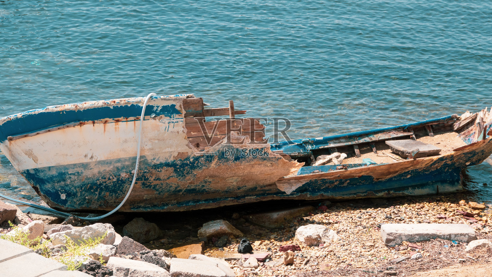 一艘破碎的木船在海边的沙滩上照片摄影图片