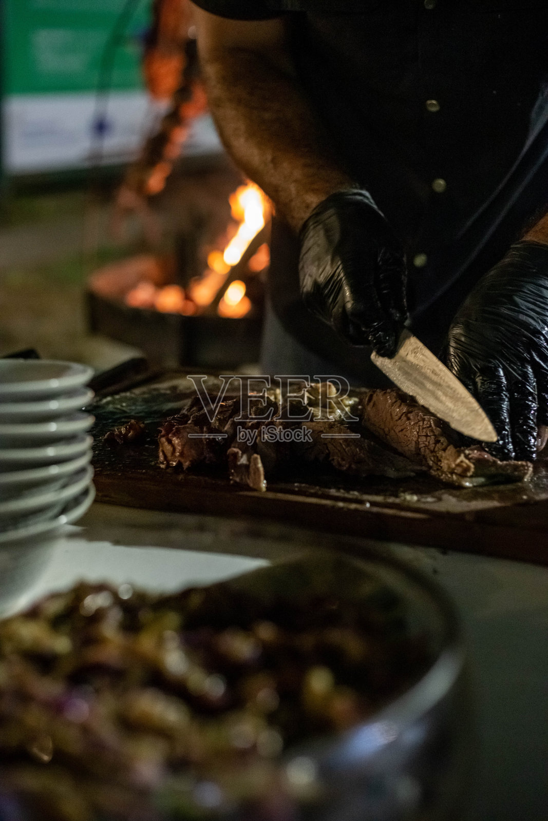厨师戴着乳胶手套在船上切烤肉。照片摄影图片