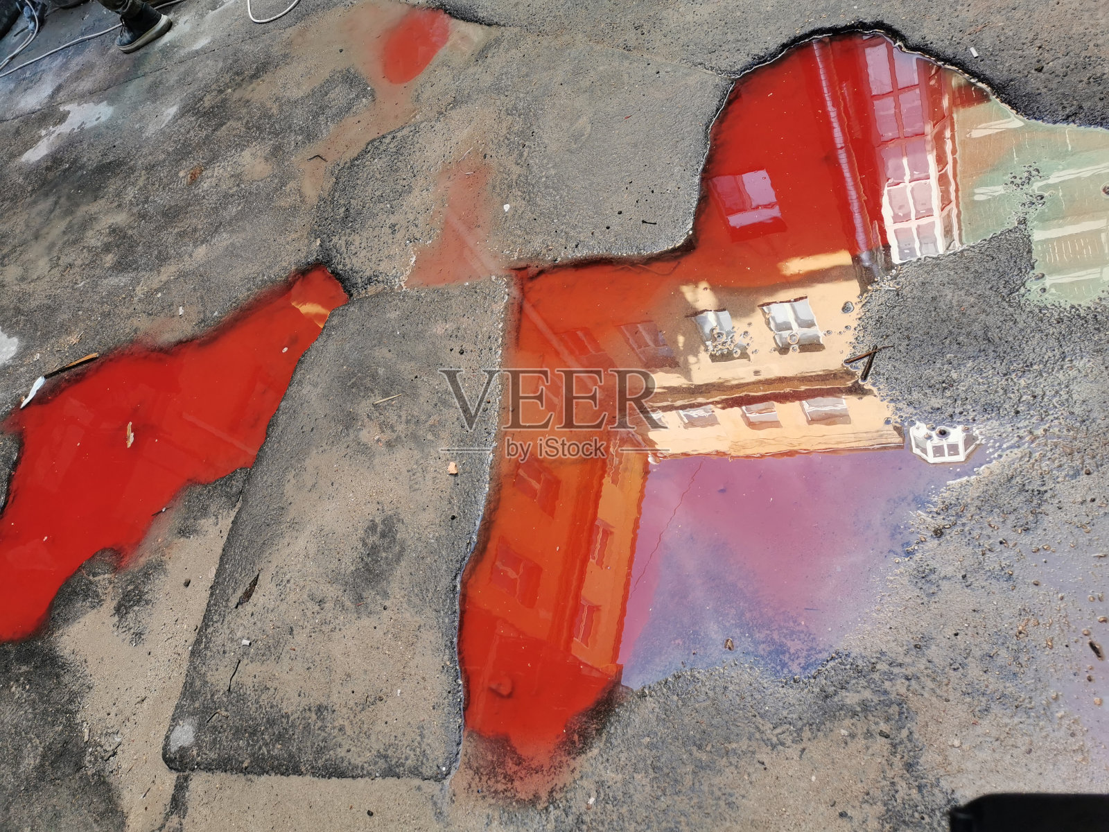 灰色沥青城市街道道路上红色水坑表面上的高层建筑倒影照片摄影图片