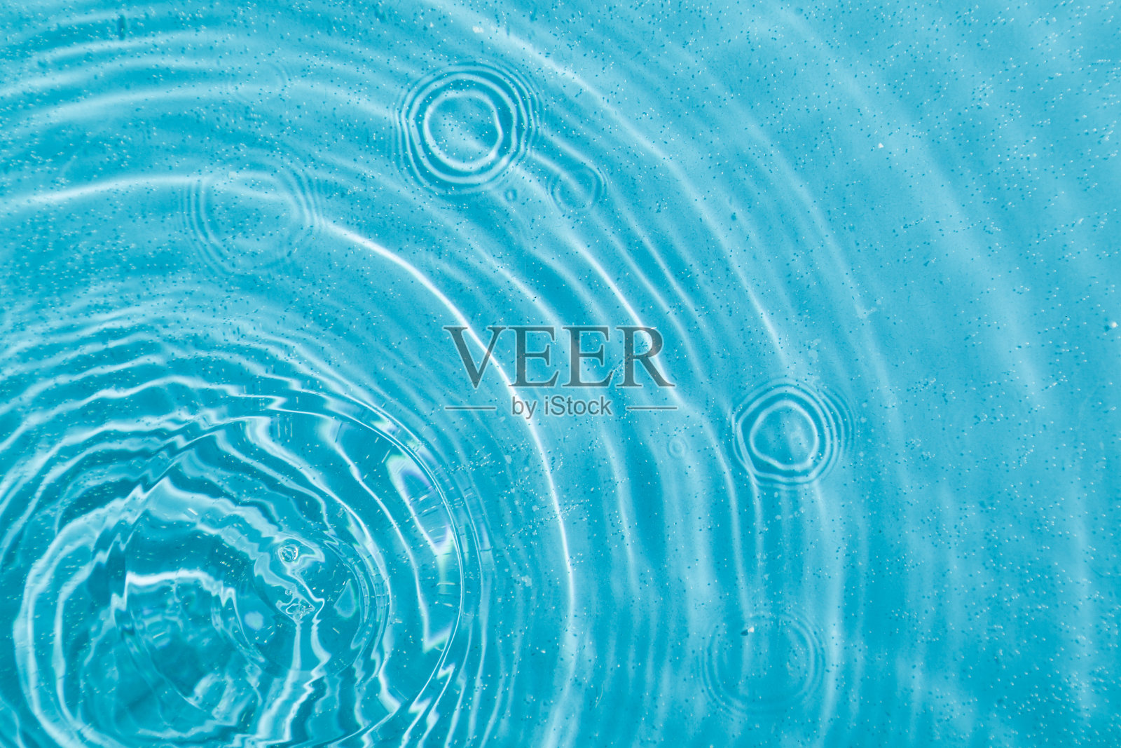 水滴在水面上，蓝色背景上有圆圈照片摄影图片