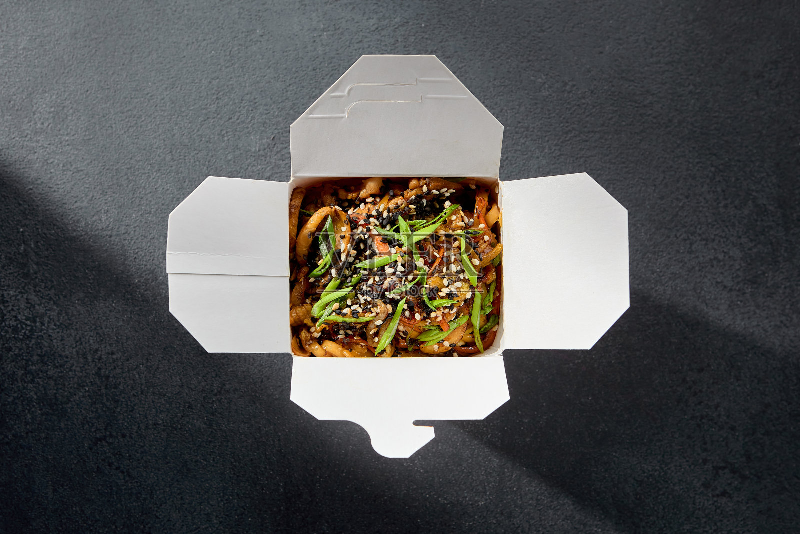 外卖概念有乌冬面、虾和海鲜，用芝麻和葱装饰在纸盒里照片摄影图片