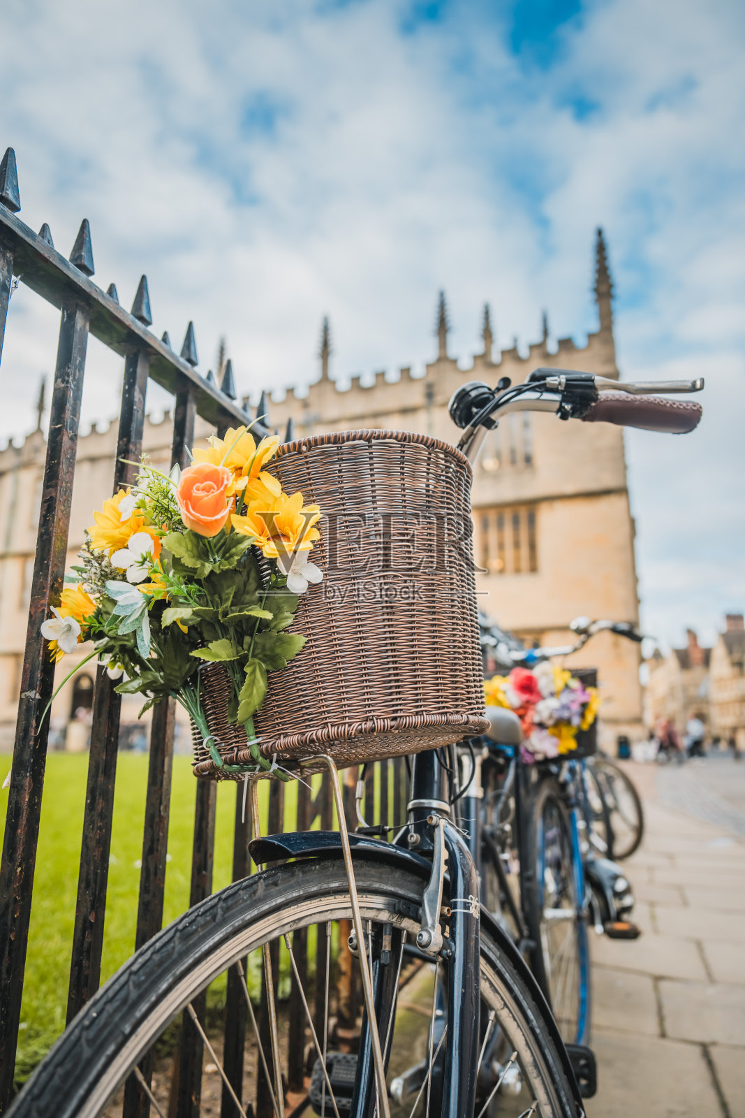 一辆粉红色的自行车靠在栅栏上，车顶上插着鲜花，这是典型的牛津景象照片摄影图片