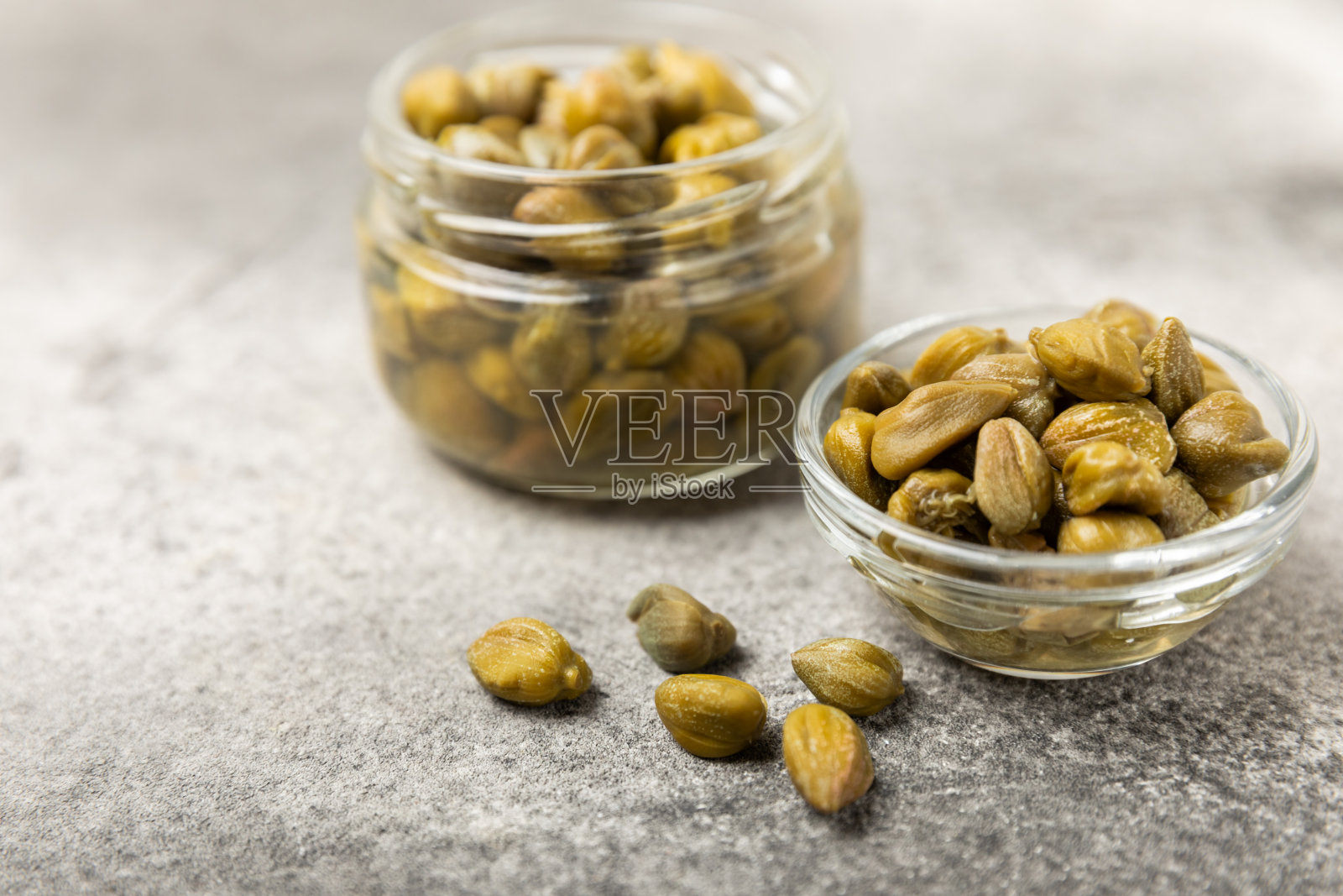 木桌上的碗里盛着刺山柑。刺山柑加海盐和迷迭香。腌酸豆。地中海菜的食材。有机香料和调味料。副本的空间。照片摄影图片