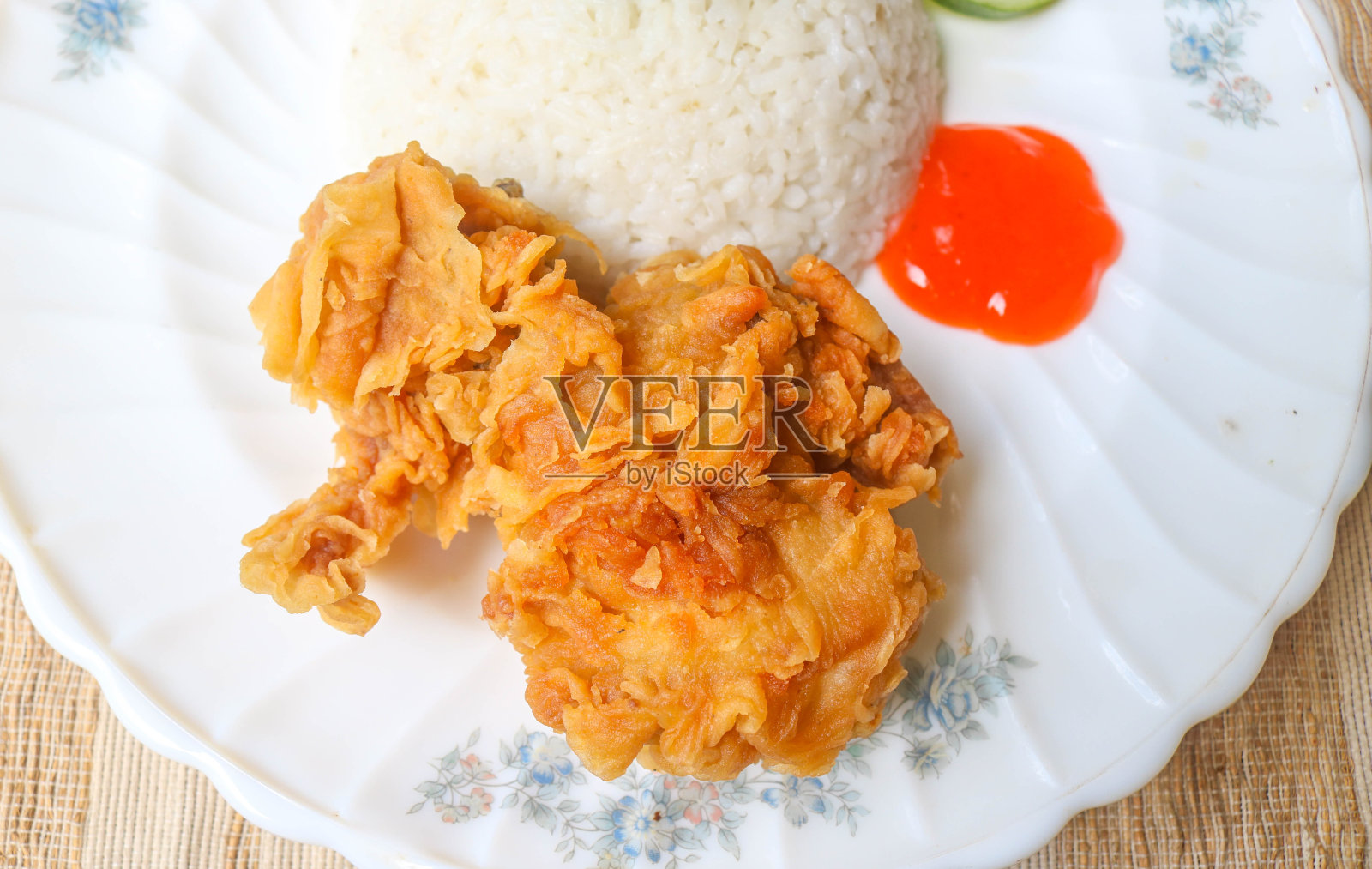 香脆的辣酱炸鸡配上米饭和黄瓜、番茄、芹菜等蔬菜作为配菜。木桌上的炸鸡和米饭照片摄影图片