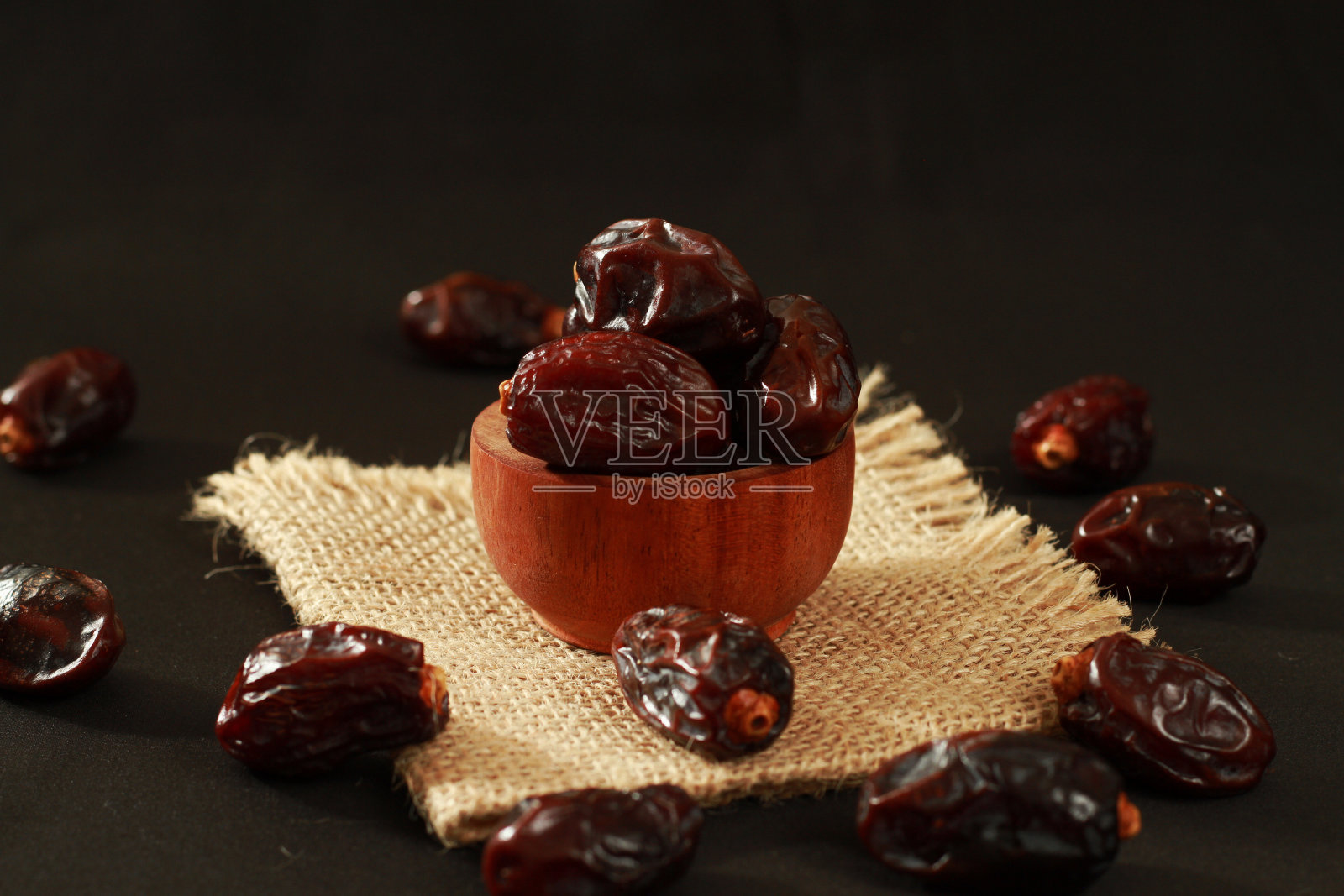 库尔玛(Kurma)或在孤立的黑色背景木碗中的枣，斋月期间流行的食物，斋月概念。照片摄影图片