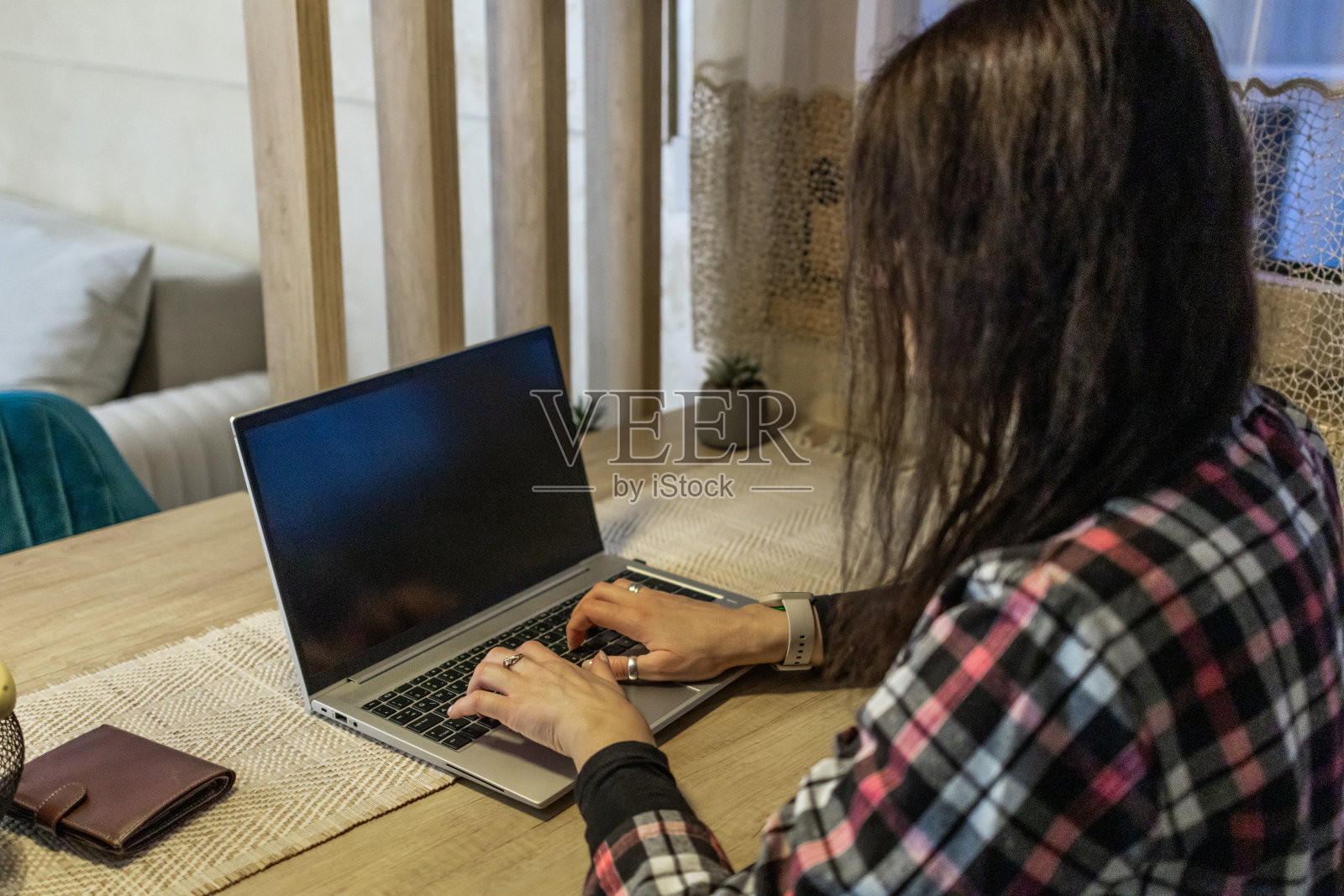 美丽的中年妇女深夜在厨房餐桌上用笔记本电脑工作。照片摄影图片