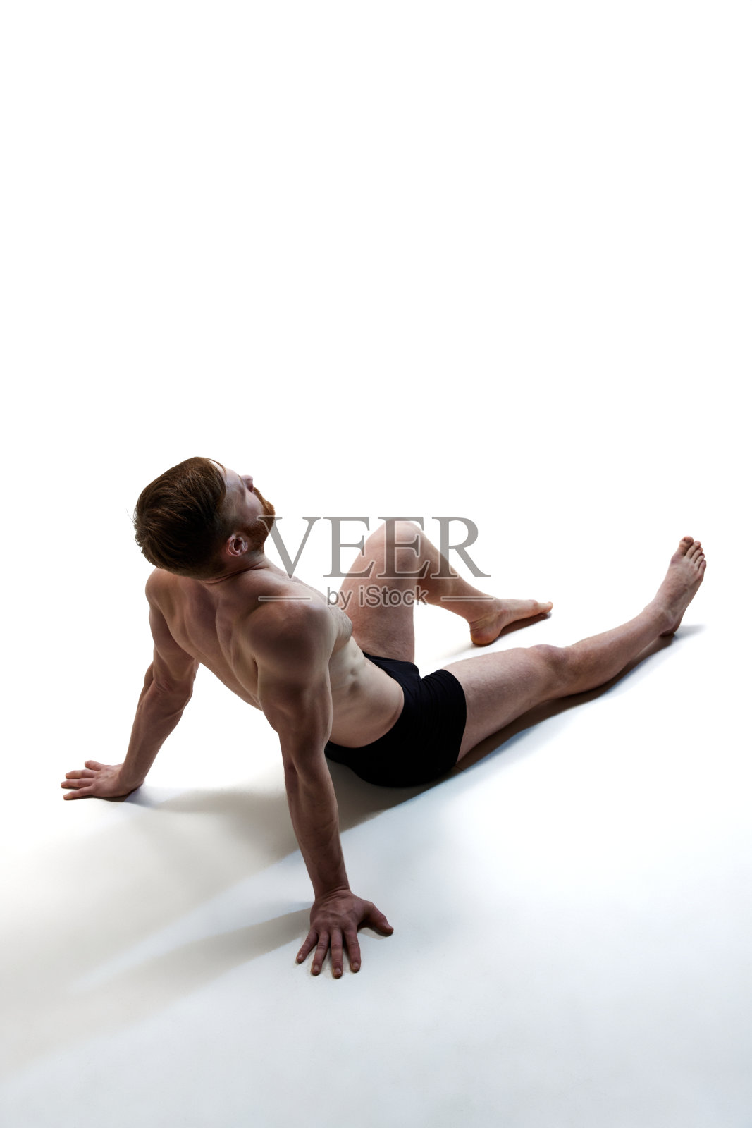男子的全身肖像，穿着内衣坐在地板上，背景是白色的工作室。健康。照片摄影图片