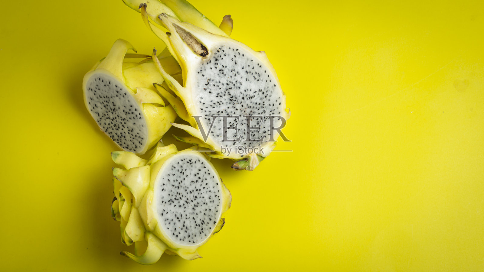 成熟的黄色火龙果对半切开，味道香甜。照片摄影图片