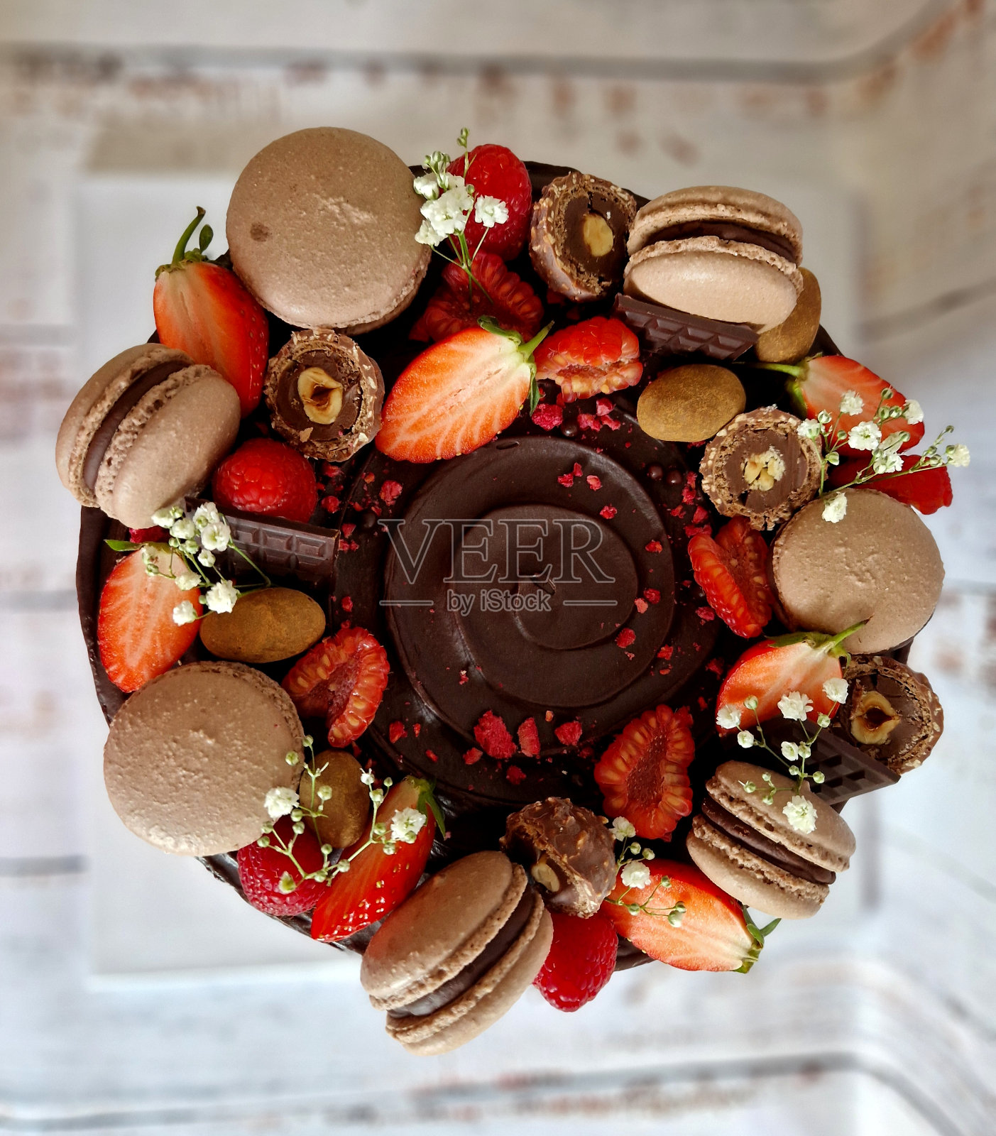 男士巧克力蛋糕糖霜。旁边的杏仁软糖盘表示出生年份。切片覆盆子和草莓。巴伐利亚围成一个圈。巴黎鲜奶油。奢侈品，皮革，花卉照片摄影图片