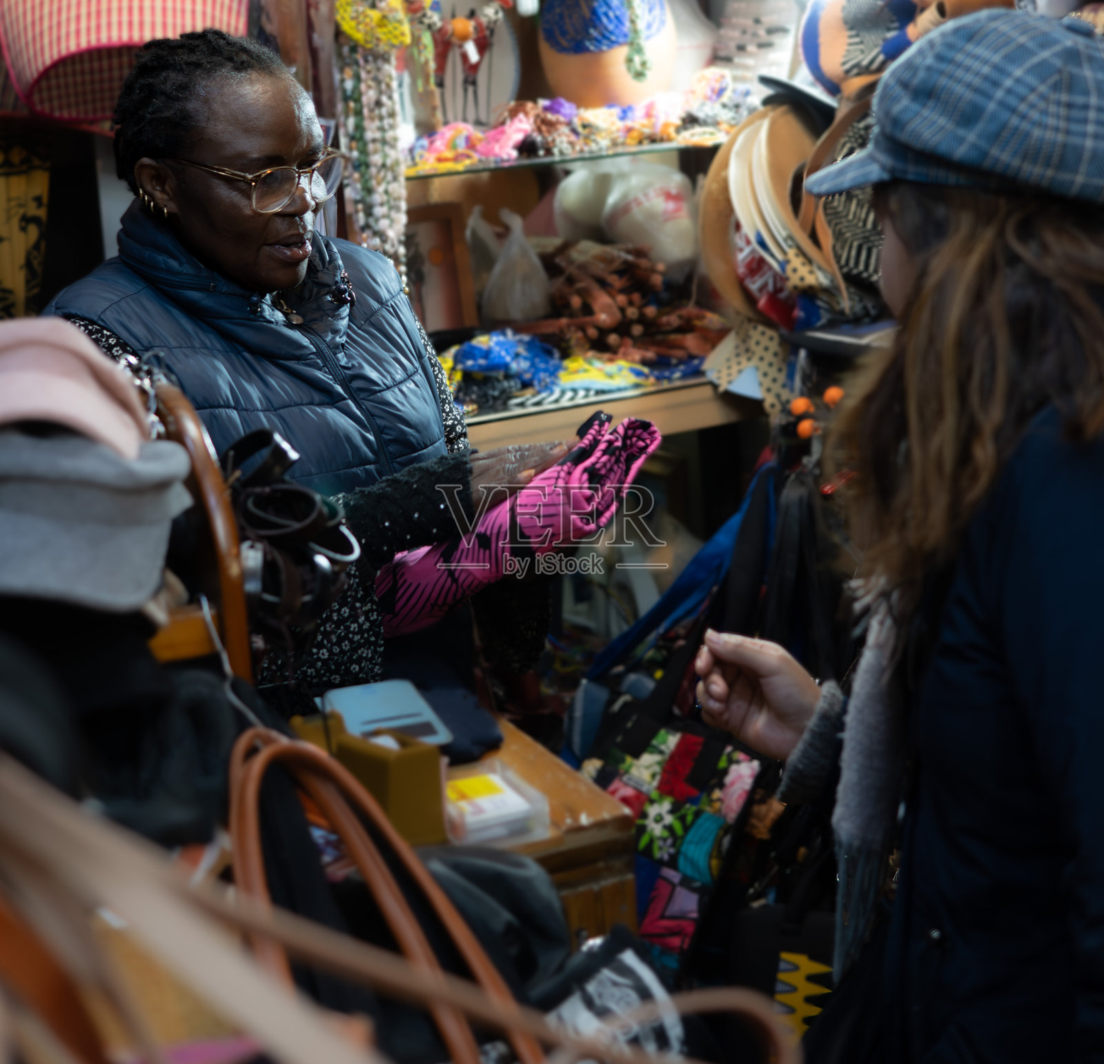 黑人祖母在她的非洲服装店向顾客出售手提包照片摄影图片