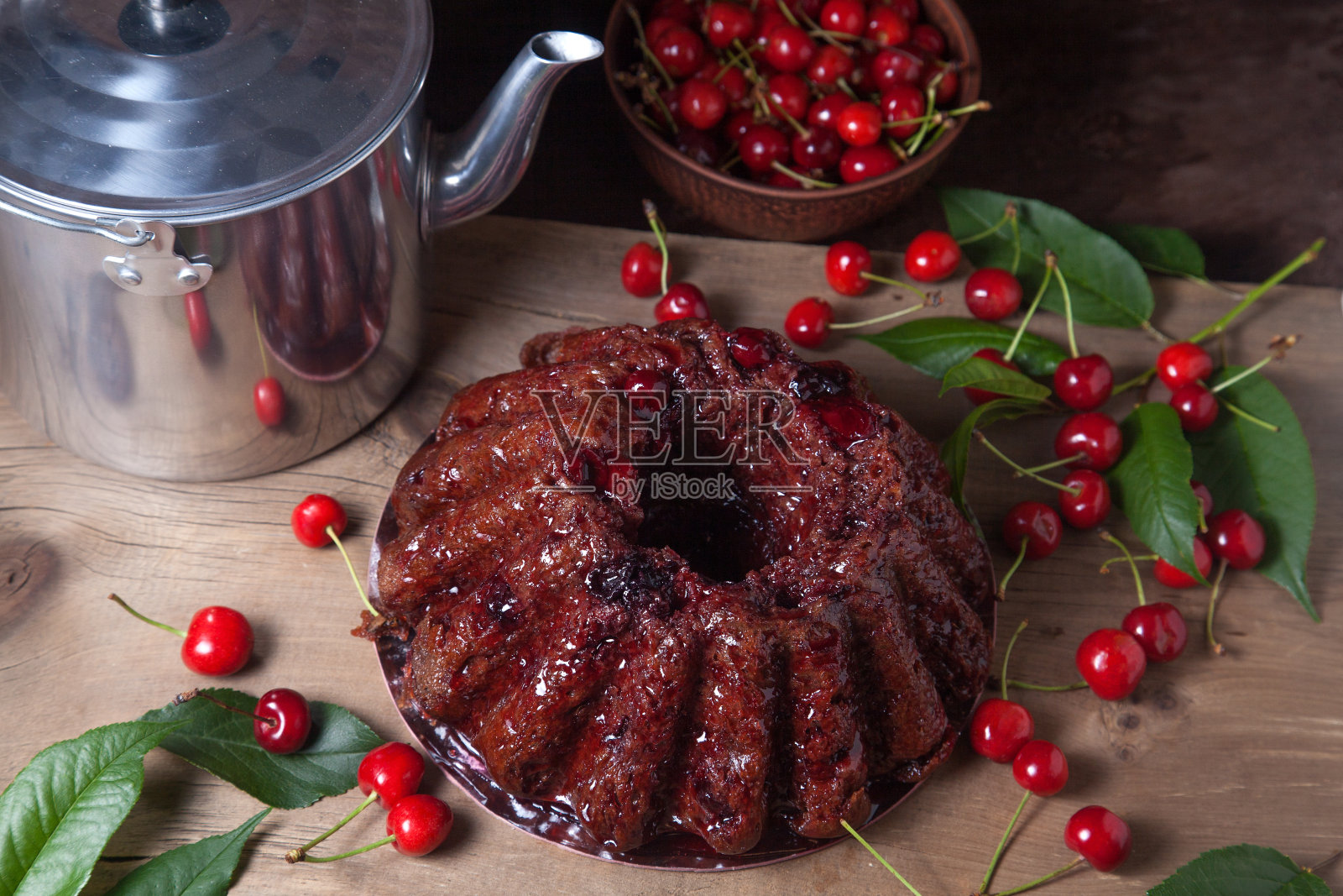 美味的巧克力蛋糕与甜樱桃和复古水壶在深色木制背景。照片摄影图片