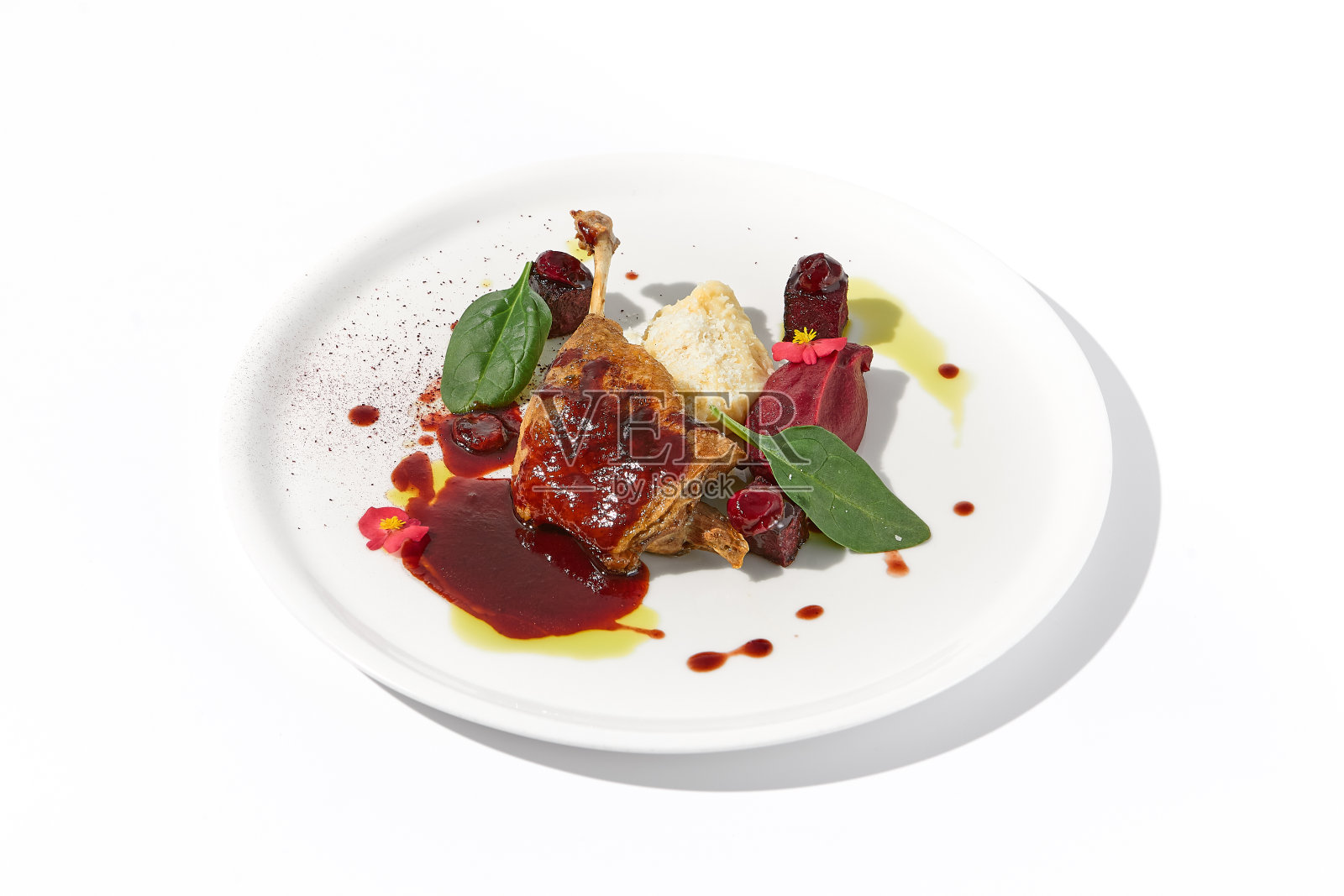浆果酱鸭腿，艺术地呈现在孤立的白色背景上，是感官的盛宴照片摄影图片