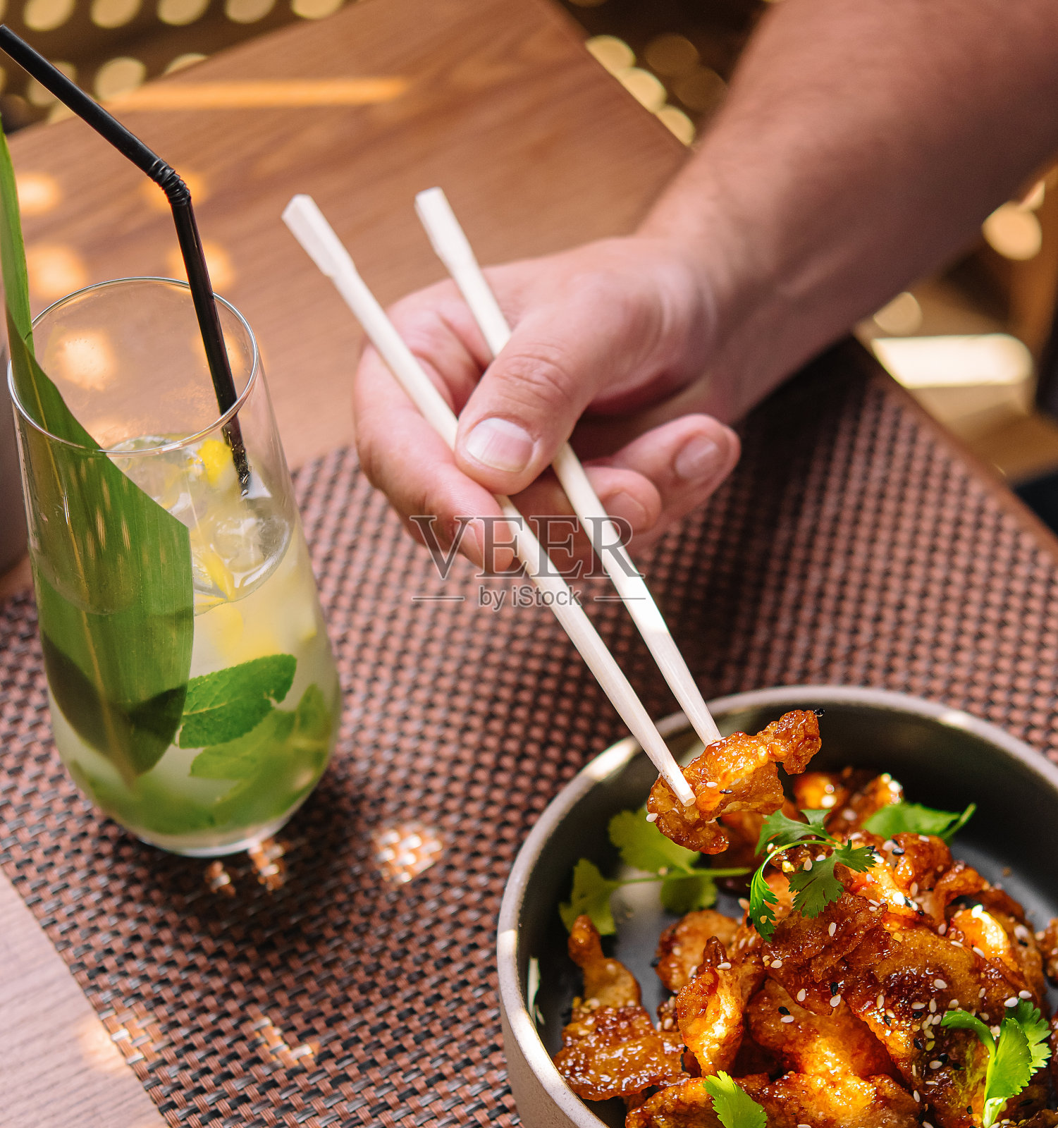 男人用筷子吃着美味的炸鱿鱼，喝着芝麻和一杯果汁照片摄影图片