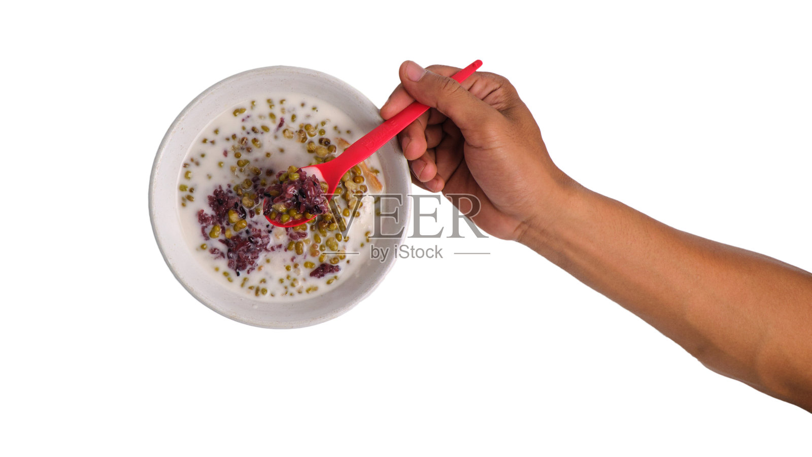 手拿着一勺青豆粥，背景是孤立的白色照片摄影图片