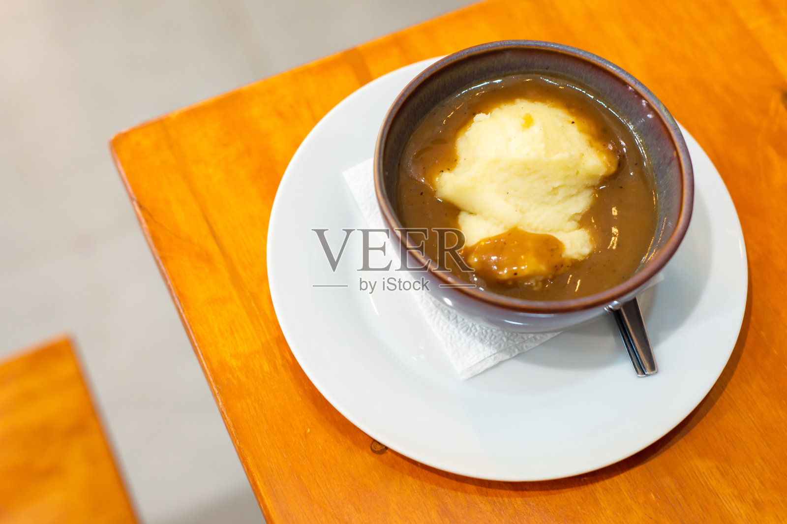 自制的土豆泥，奶酪和肉汁放在棕色的碗里，白色的碟子放在餐馆的木桌上照片摄影图片