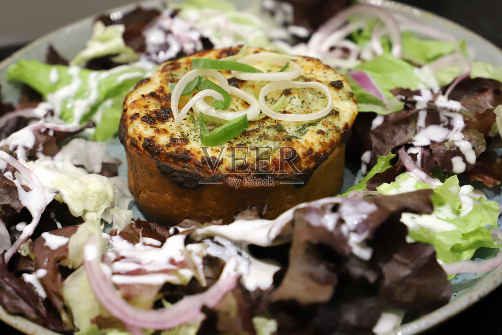 大蒜和乳清干酪蛋挞，配以红洋葱和自制蛋黄酱的绿色沙拉。照片摄影图片