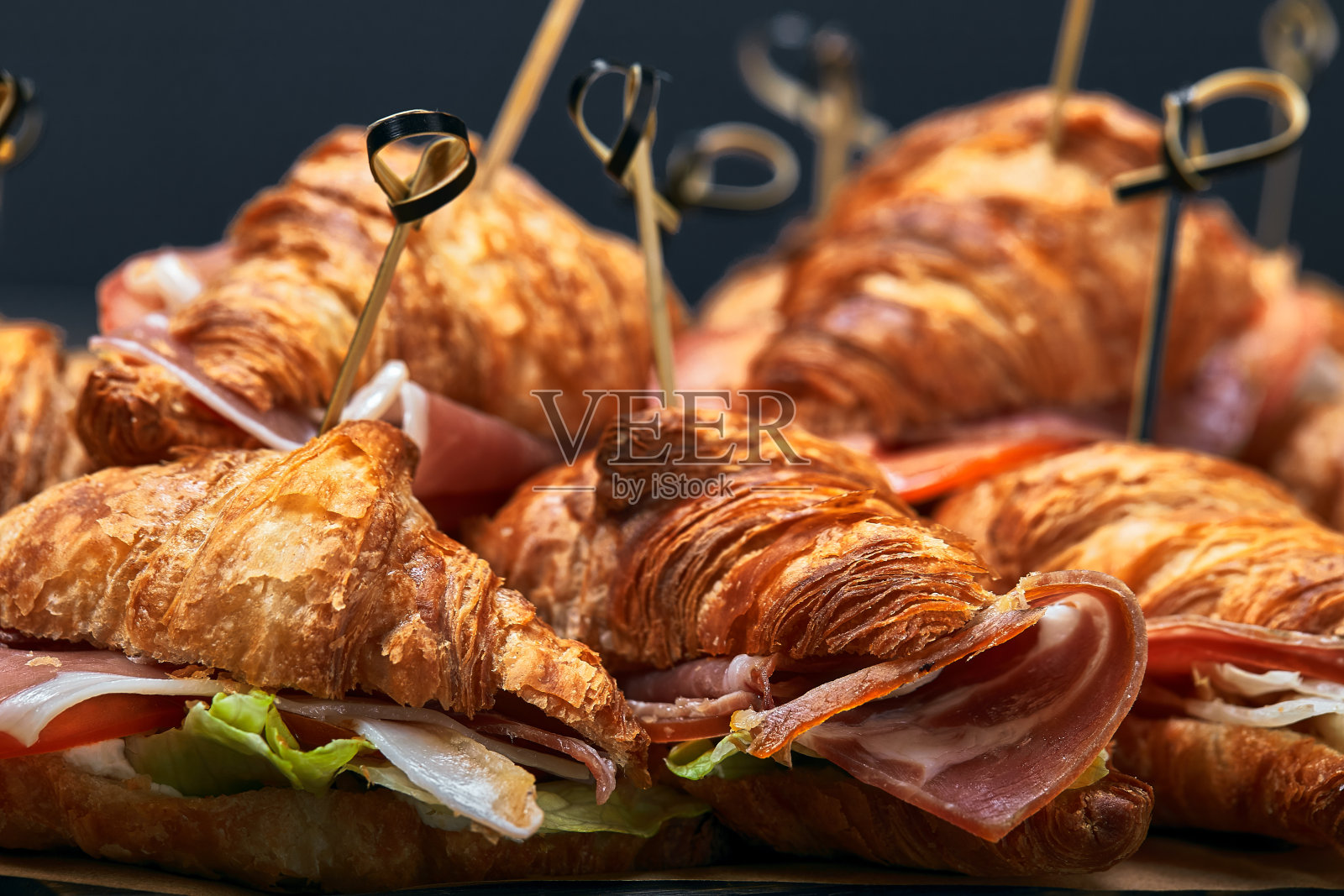 灰色背景的桌子上摆放着一大堆不同馅料的羊角面包。赛斯快餐。灰色背景，复制空间。照片摄影图片