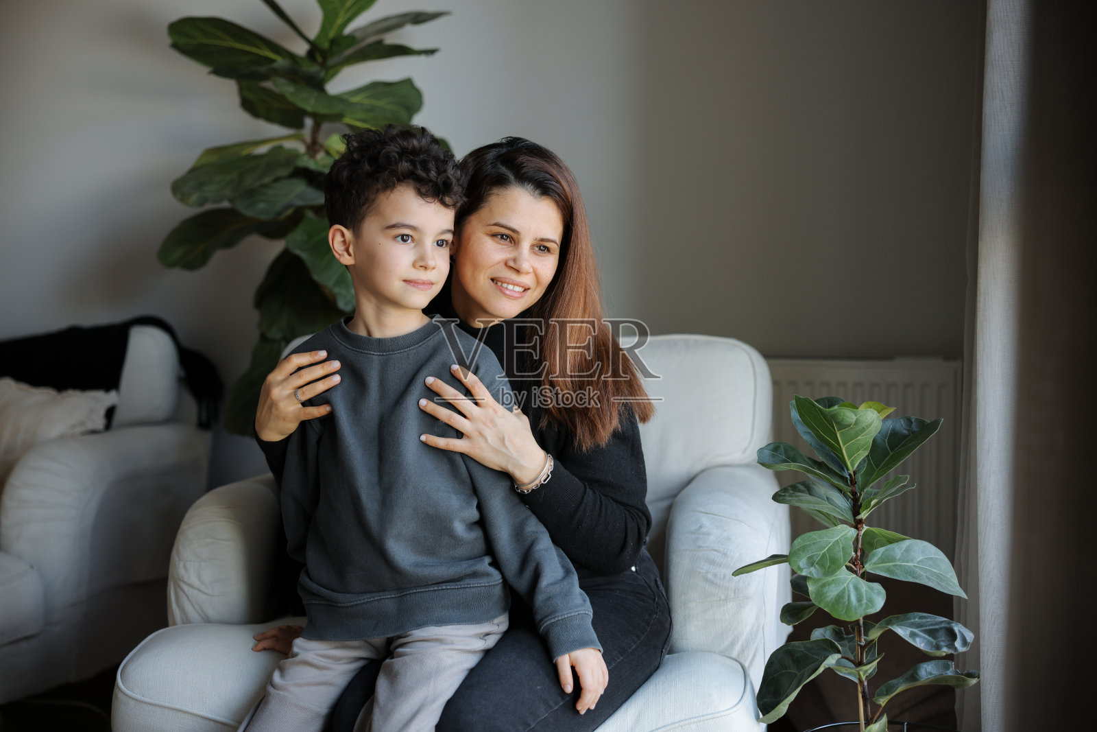 年轻女子和她的儿子早上在沙发上见面照片摄影图片