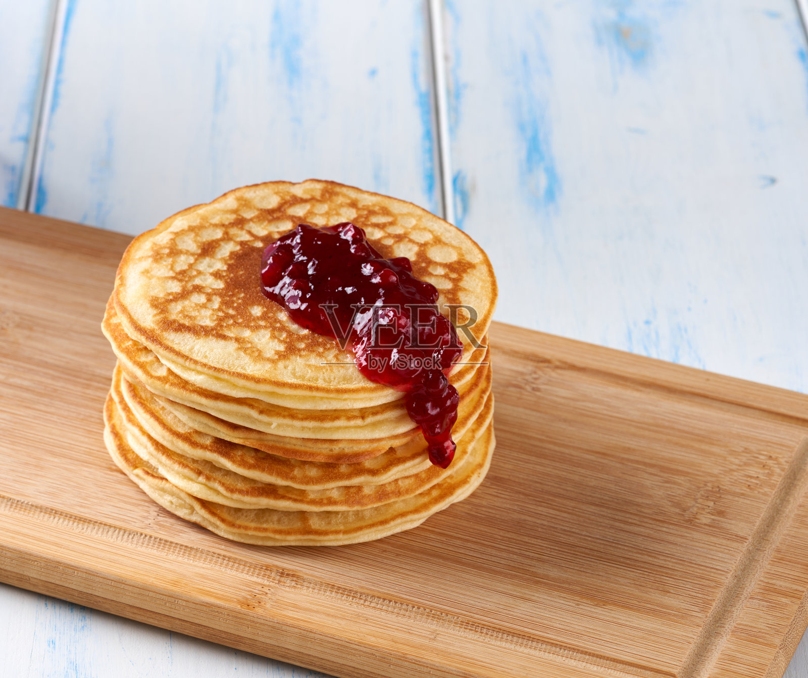 木桌上放着红莓果酱煎饼。照片摄影图片