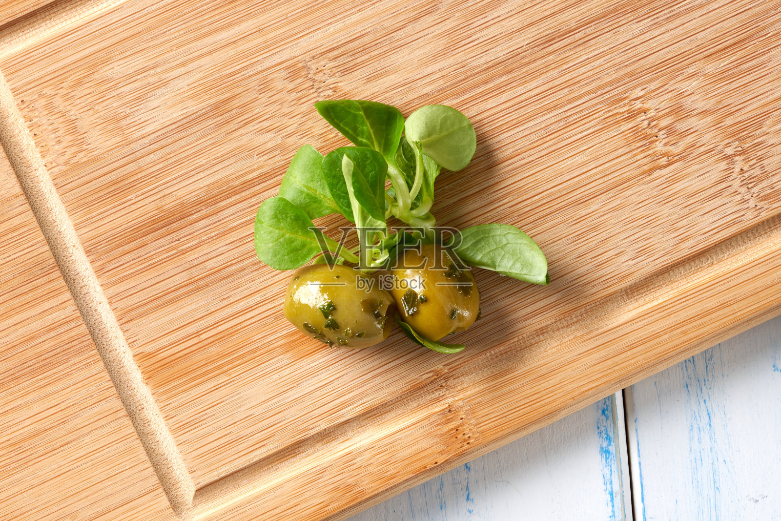 橄榄和绿色香草放在砧板上。照片摄影图片