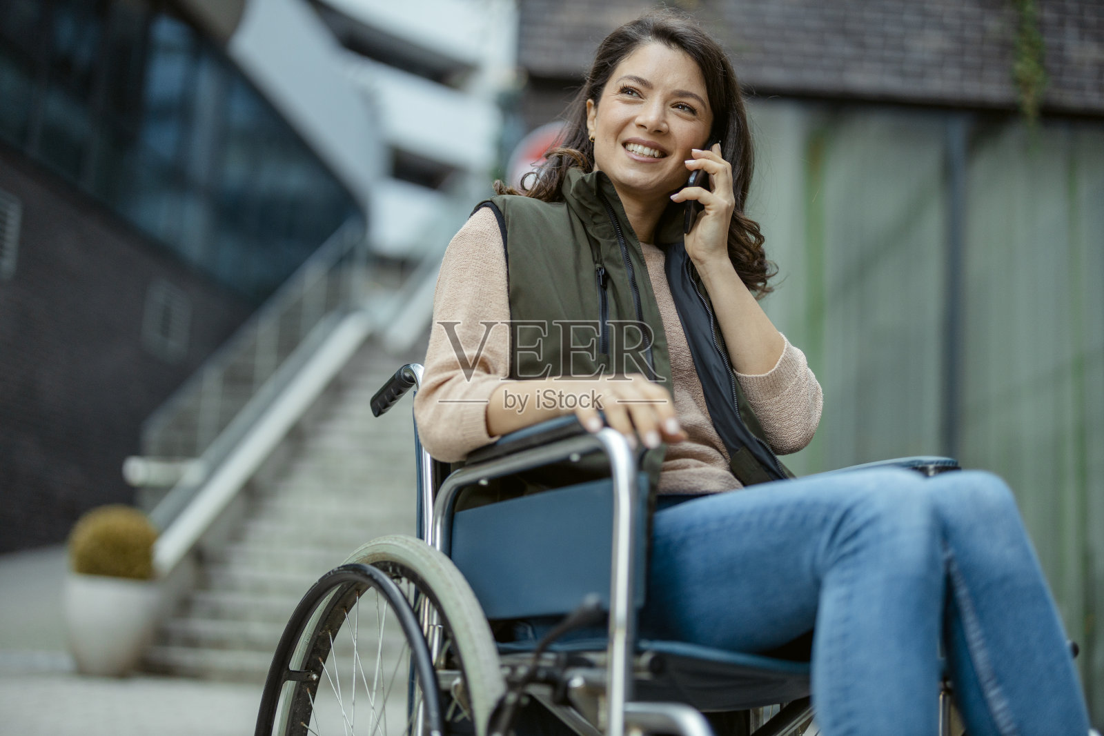 坐在轮椅上的残疾女性用智能手机与他人交谈照片摄影图片