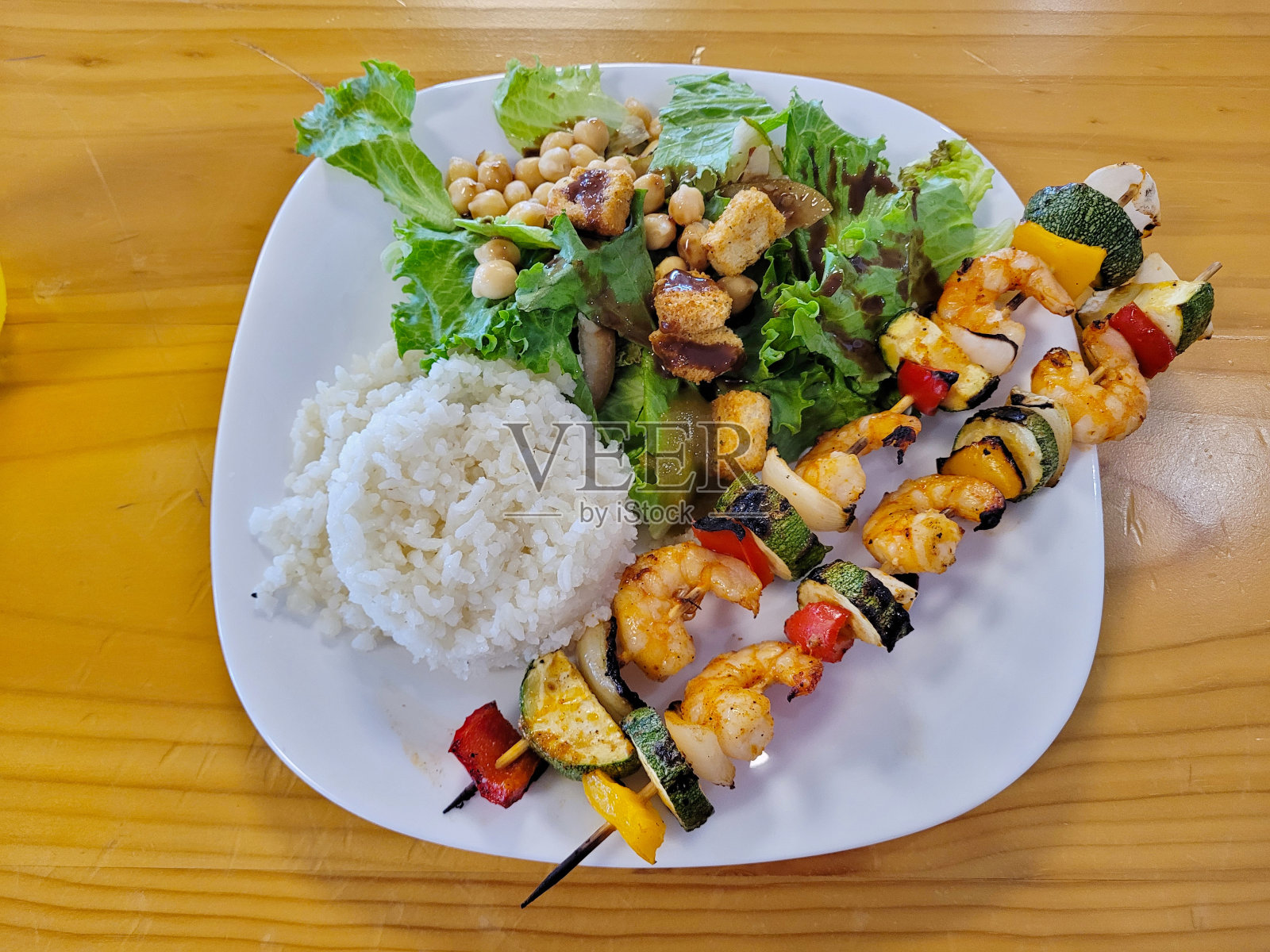 木桌上的串饭和沙拉照片摄影图片