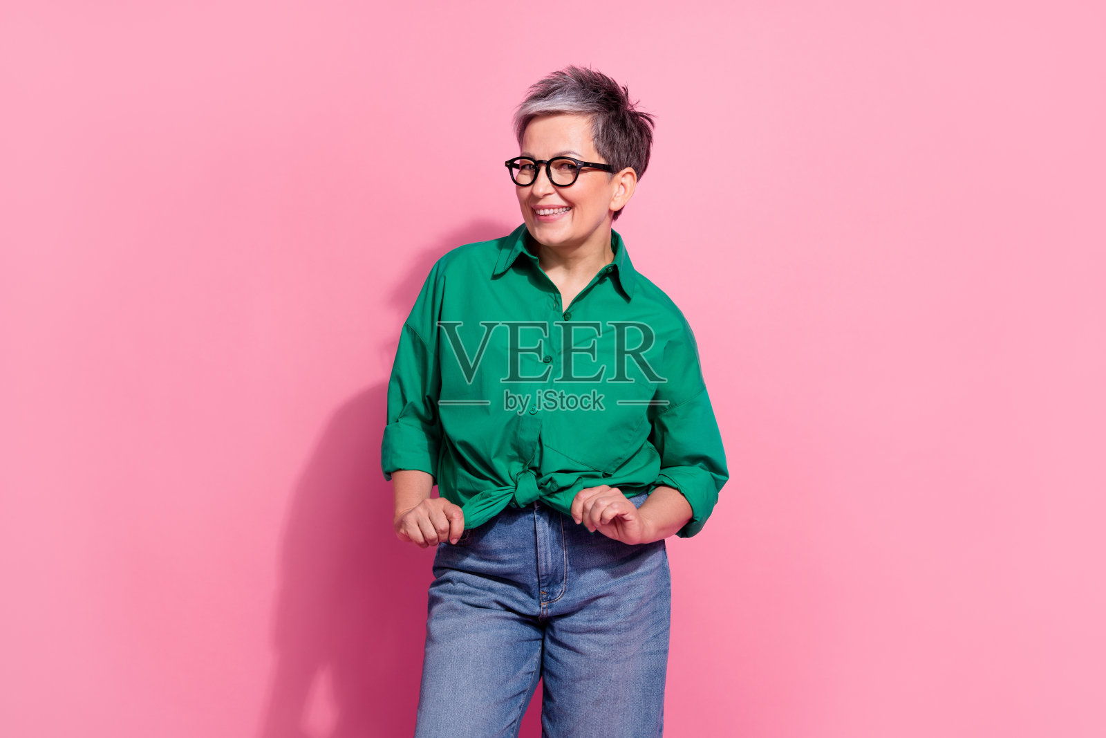 照片肖像有吸引力的退休妇女摆出领带蝴蝶结衬衫，穿着时尚的绿色衣服孤立在粉红色的背景照片摄影图片