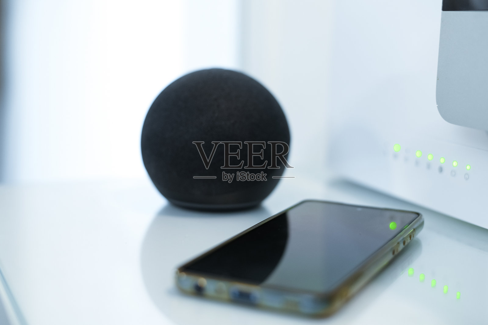 桌上有智能手机、wifi扬声器、路由器和电脑。技术、家居、家庭自动化理念照片摄影图片