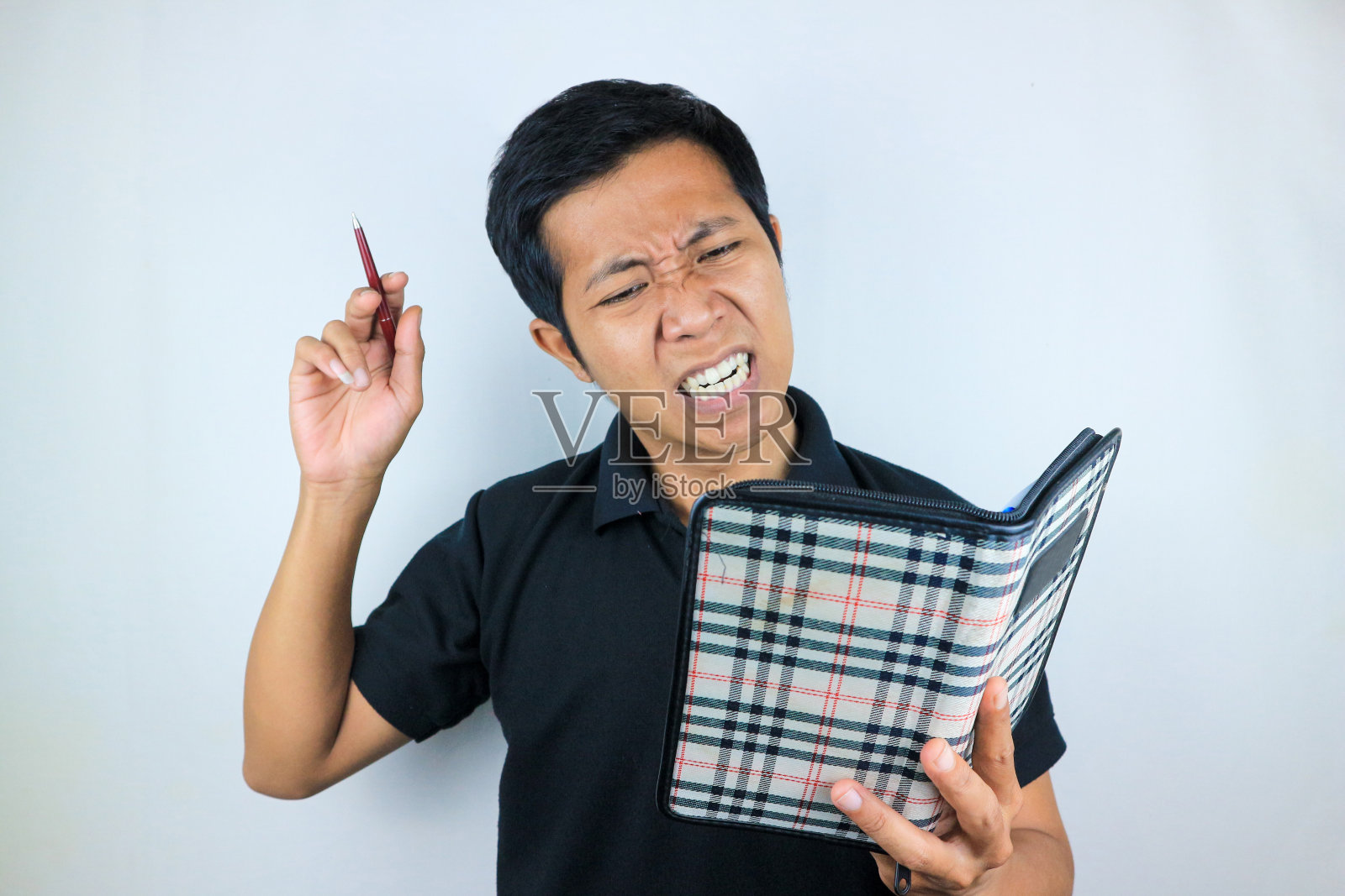 一个拿着笔和笔记本的亚洲人的令人晕眩的面部表情，孤立在白色的背景上照片摄影图片