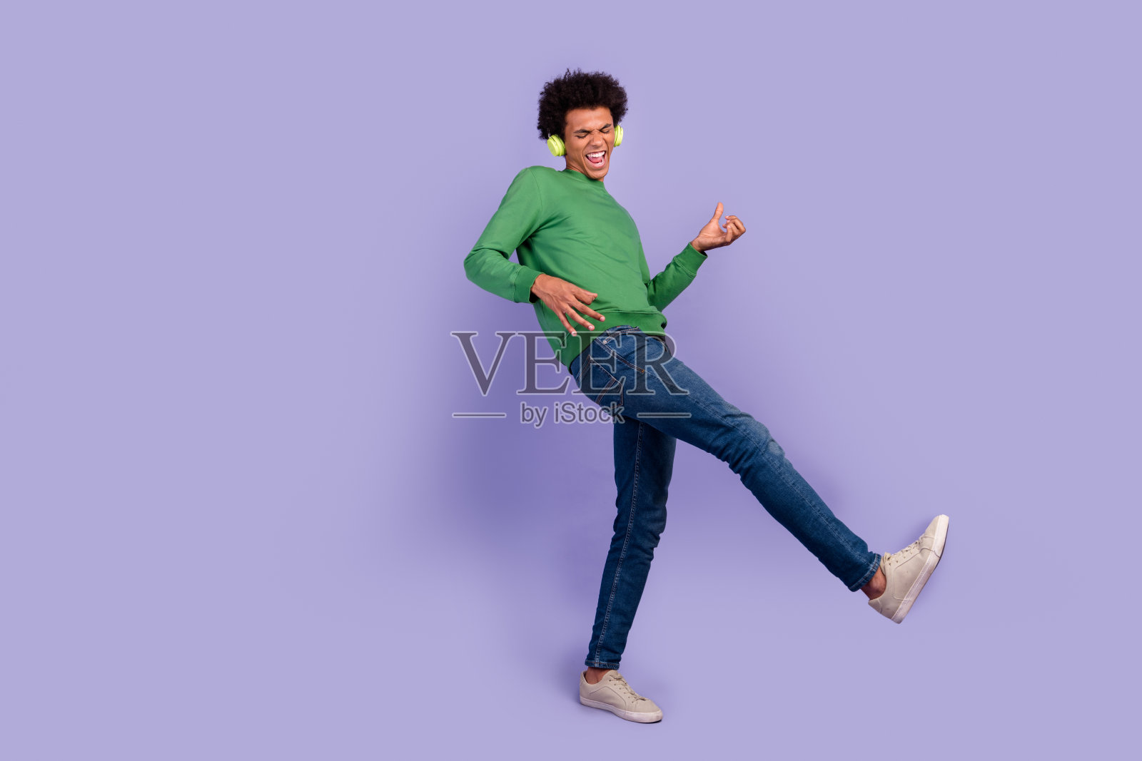 照片上时髦酷的家伙戴着绿色套头耳机弹奏音乐吉他空旷的空间孤立的紫色背景照片摄影图片