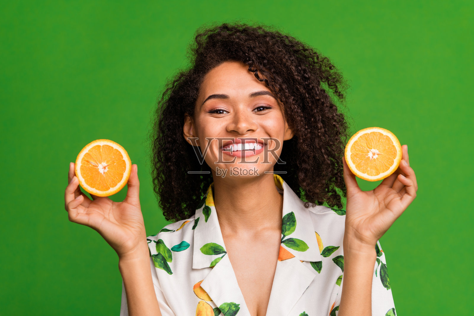 照片的漂亮开朗的女人穿着印花衬衫上升两个橙色的一半孤立的绿色背景照片摄影图片